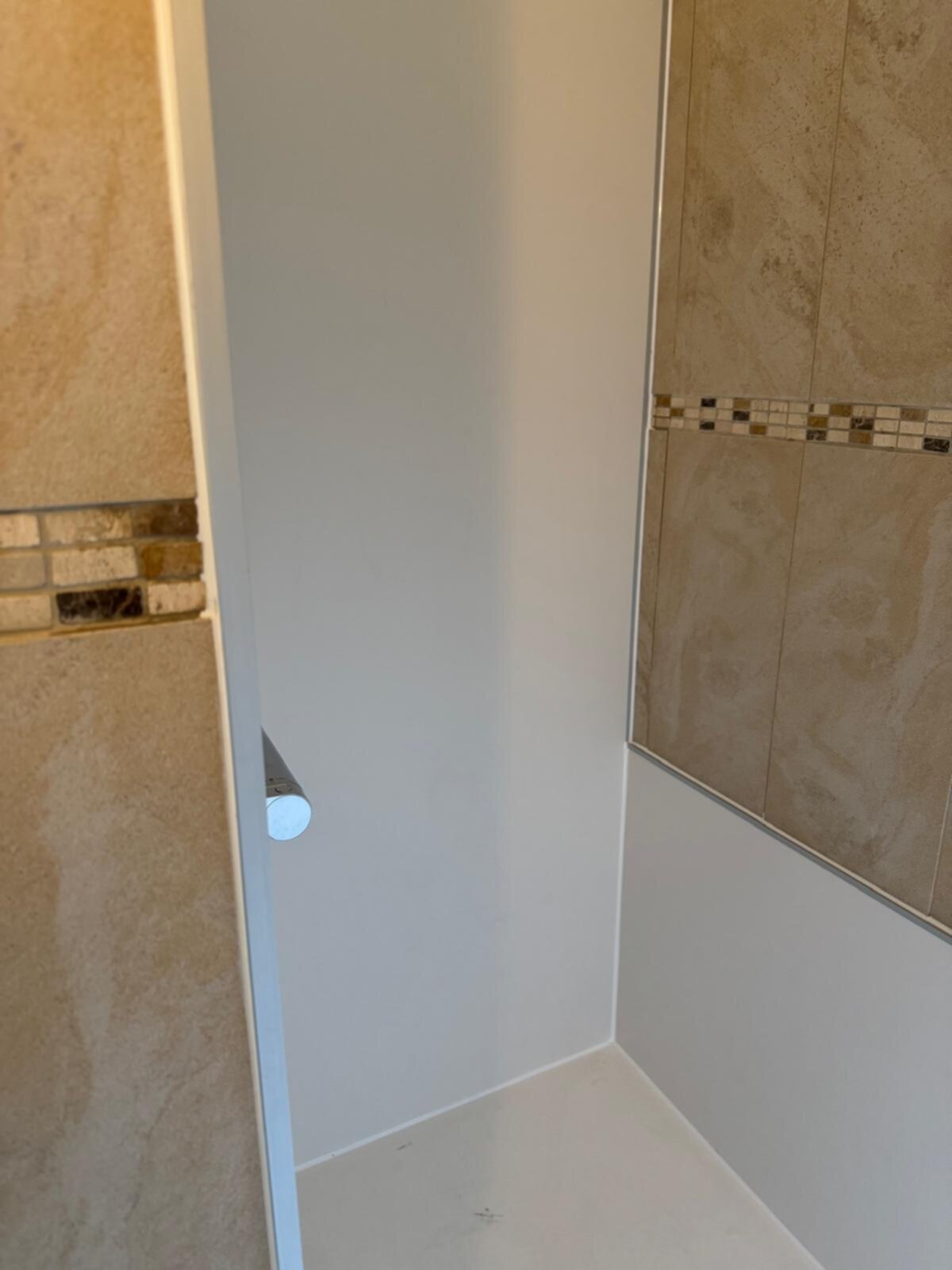Douchehoek met beige tegels en witte wand