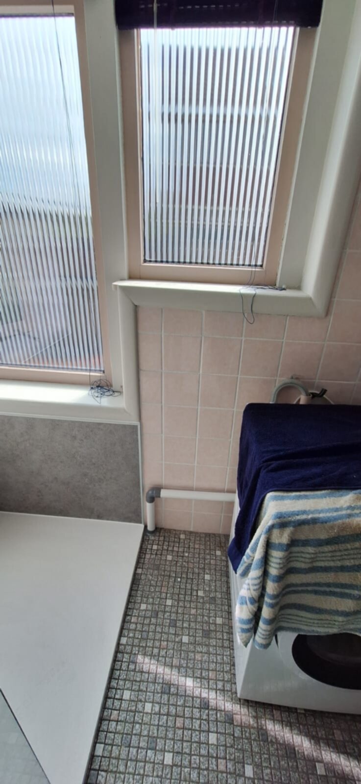Badkamer met wasmachine en betegelde muren en vloer