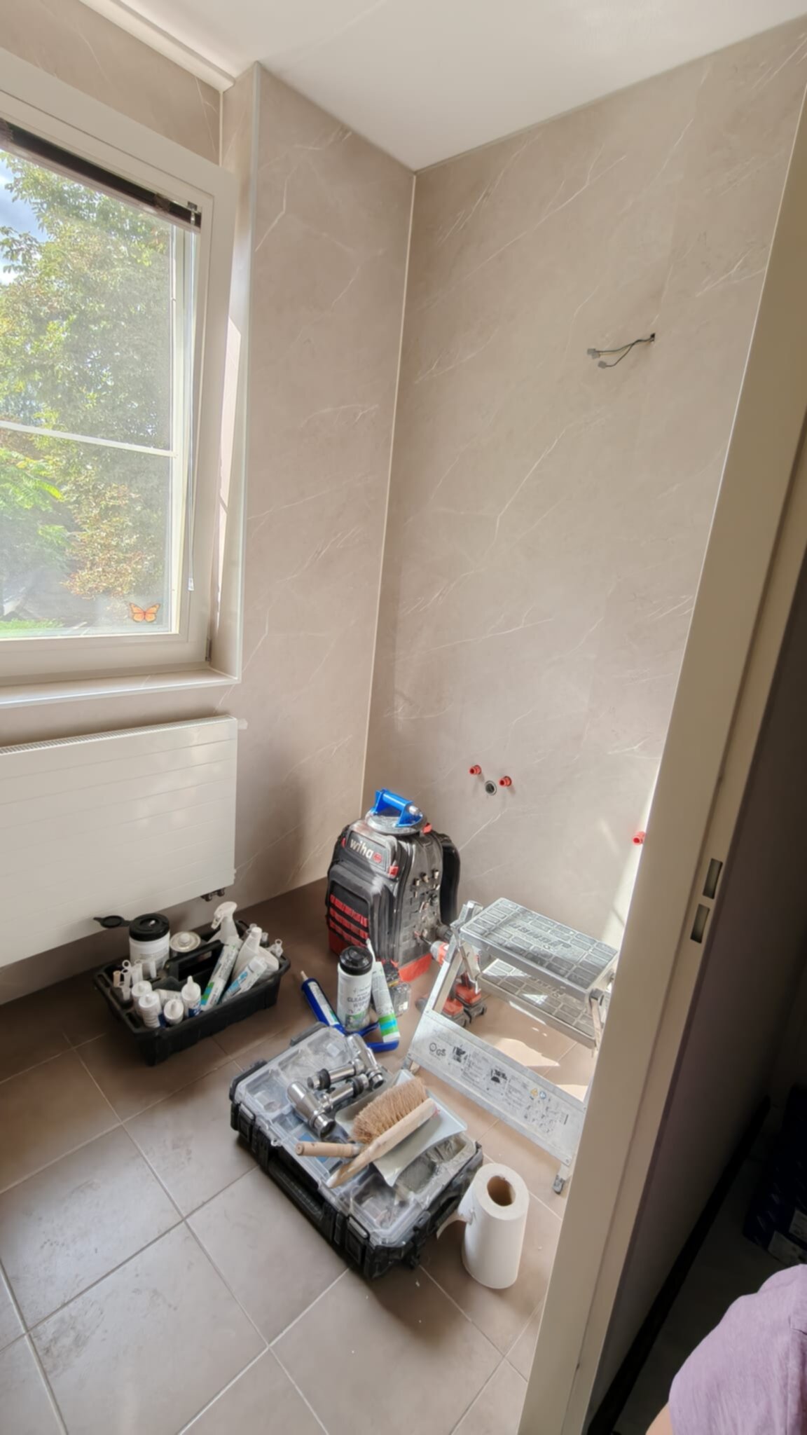 Tijdens badkamer renovatie, beige marmerlook tegels, gereedschap en materialen op de vloer