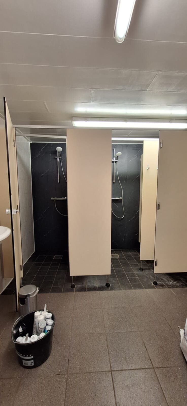Badkamer met twee douchecabines en betegelde vloer en muren