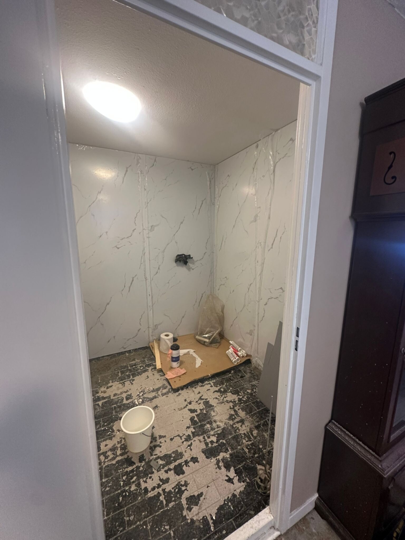 Badkamer in renovatie, marmerlook tegels op de muur, kale vloer