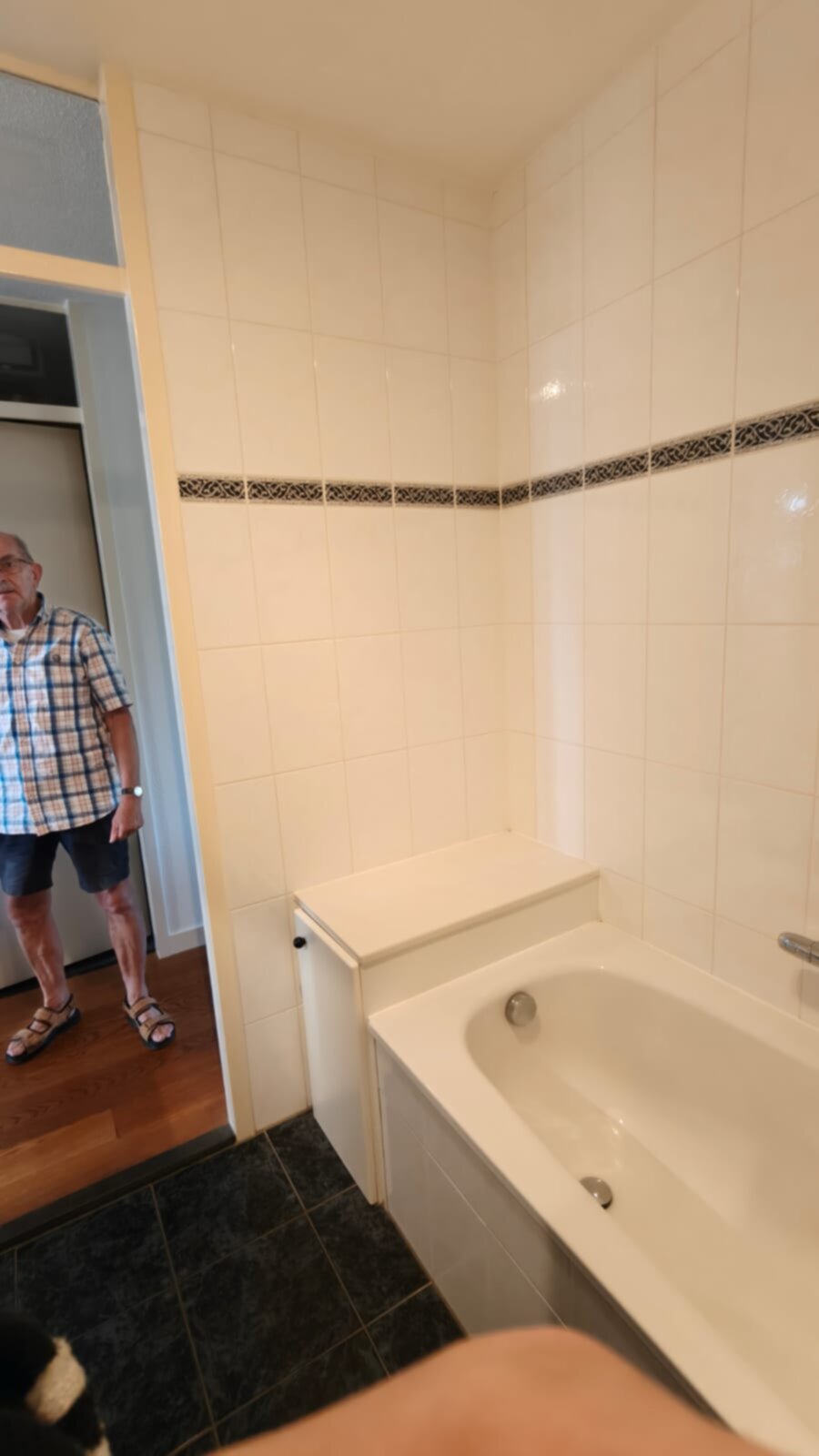 Wit betegelde badkamer met zwarte vloer en badkuip