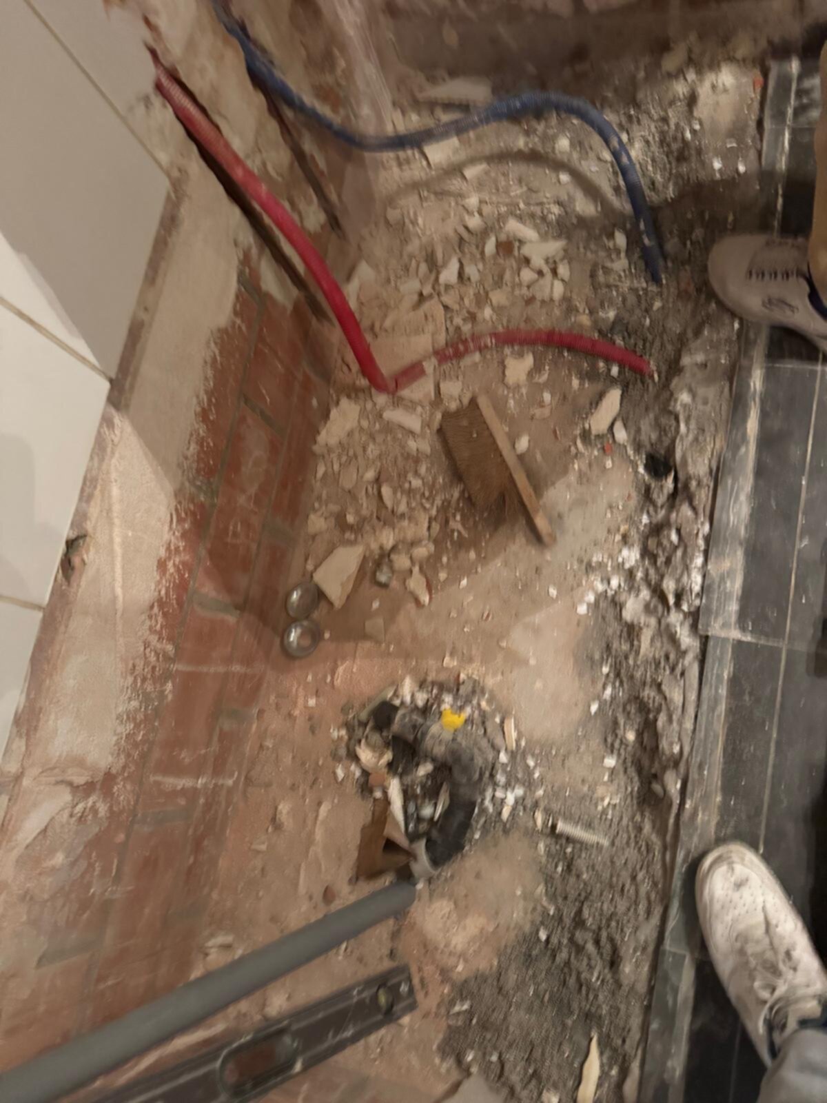 Sloopwerkzaamheden in badkamer met blootgelegde leidingen en puin