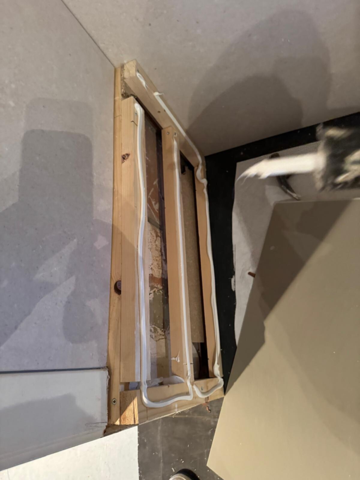 Open badkamer tijdens renovatie met zicht op de betegelde muren en houten frame