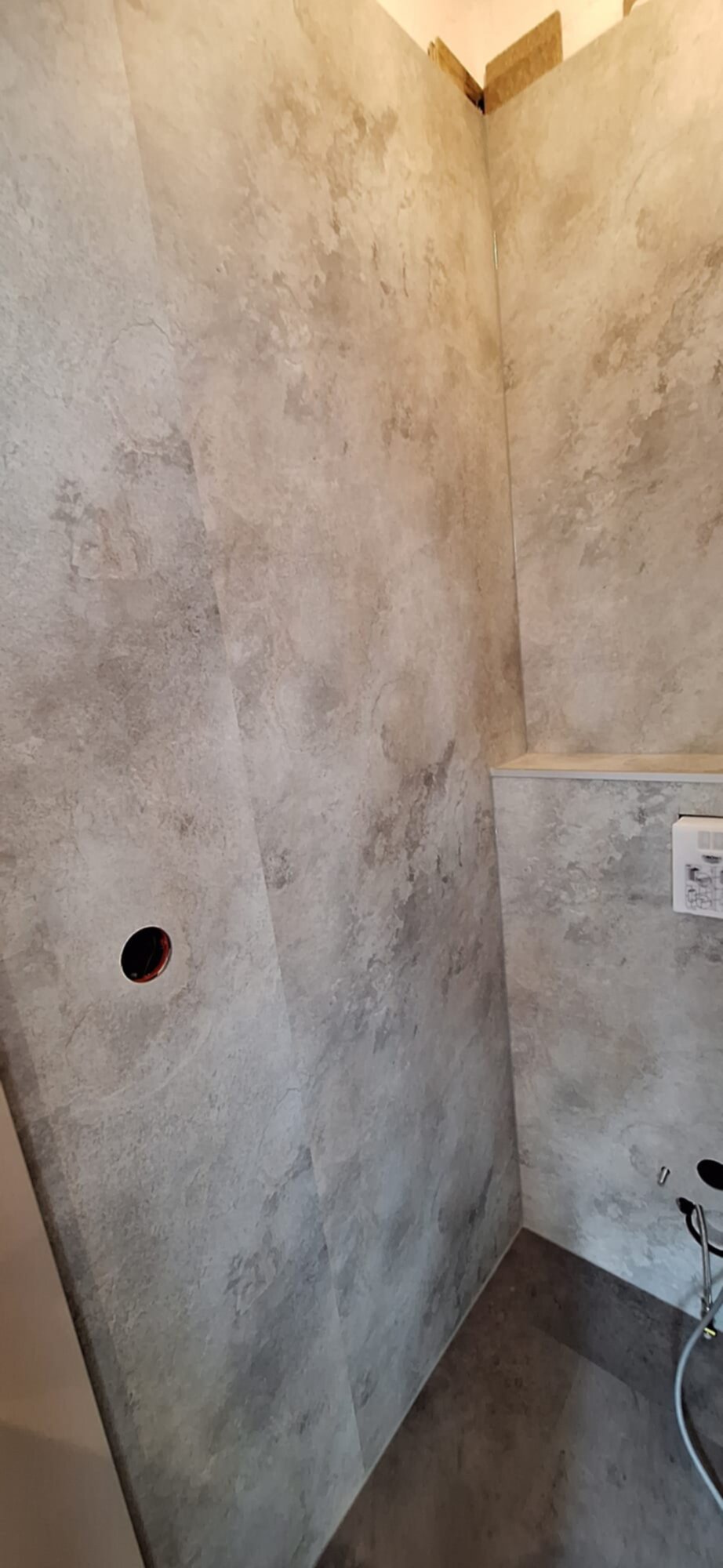 Grijze betegelde badkamer wand met betegelde vloer en ingebouwde nis