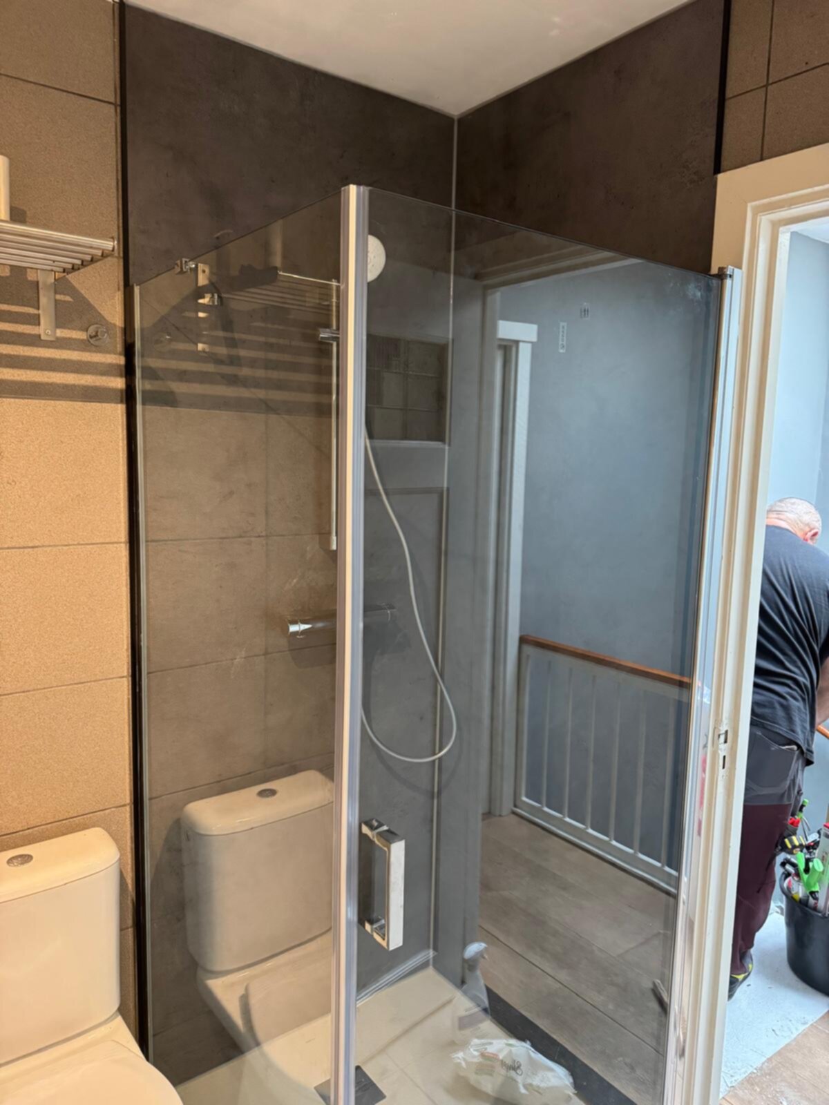 Badkamer tijdens renovatie met glas, tegel, toilet en werker