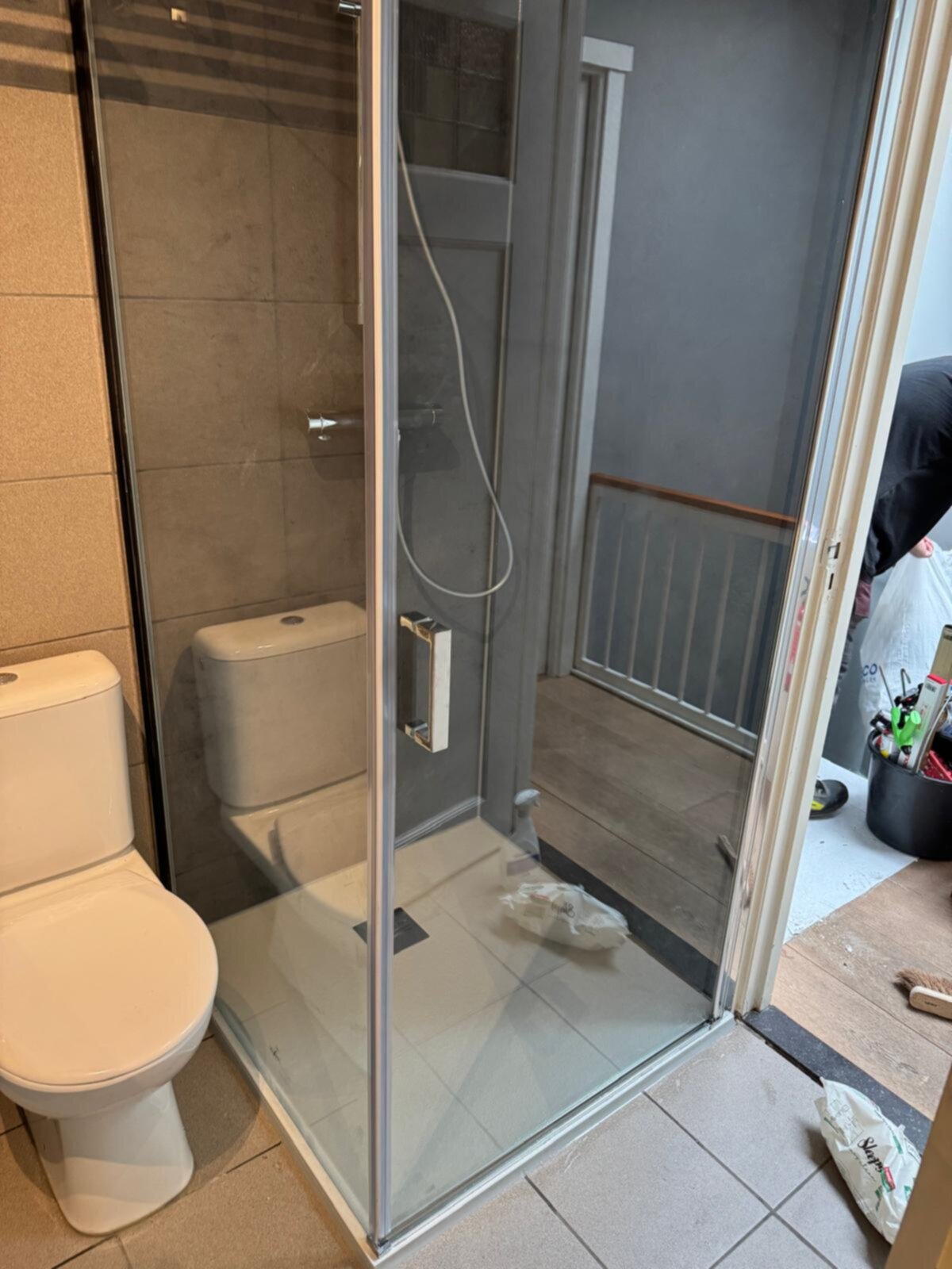 Badkamer met witte toilet en glazen douchecabine tijdens renovatie