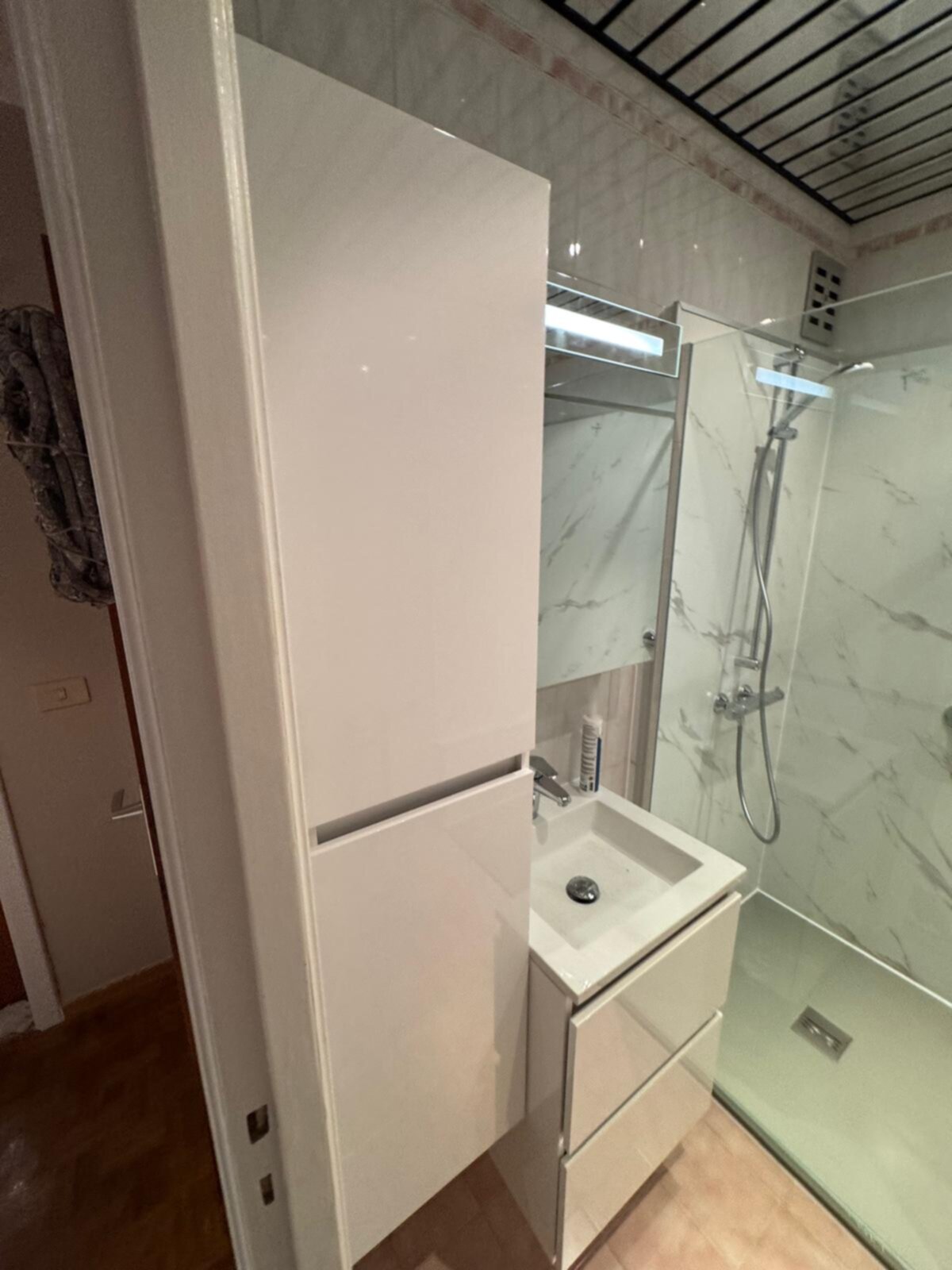Moderne badkamer met witte marmeren tegelwand, glazen douchecabine en witte wasbak