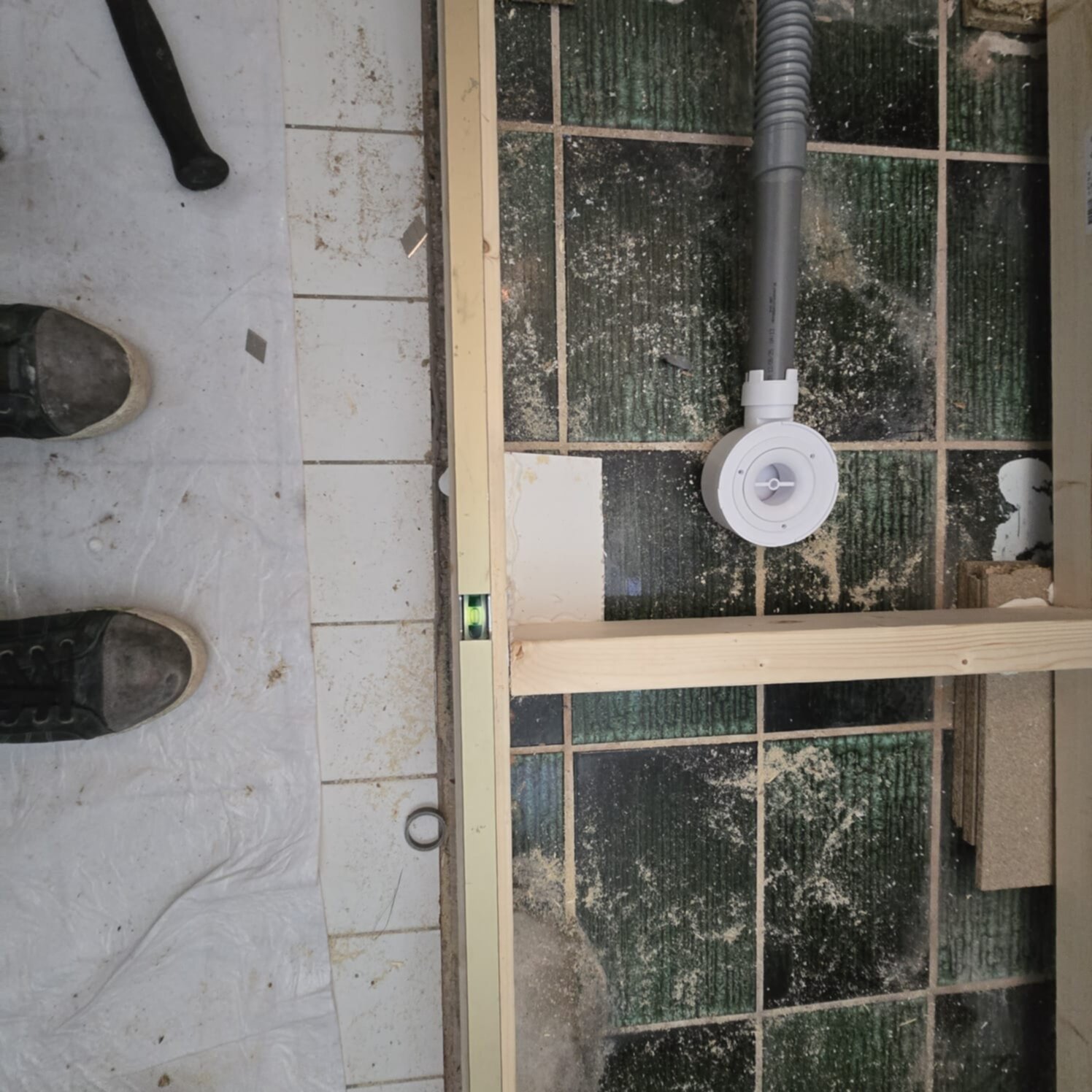Een werksituatie tijdens badkamer renovatie met hout, gereedschap en oude tegels