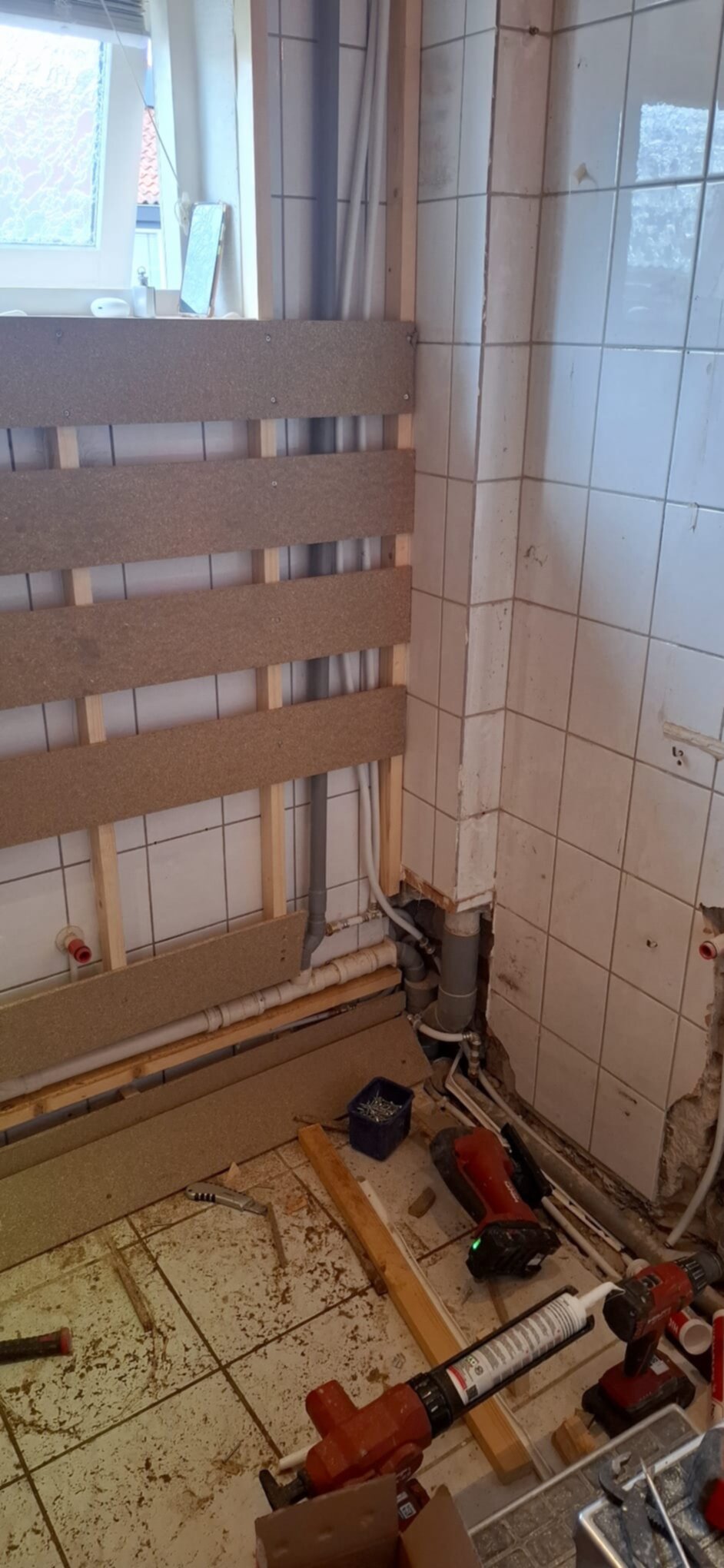 Badkamer renovatie in uitvoering, zicht op betegelde muur en gereedschap