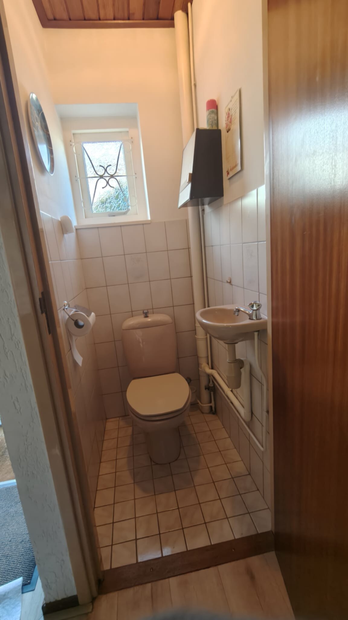 Kleine badkamer met toilet en wastafel, witte tegels en beige kleuren