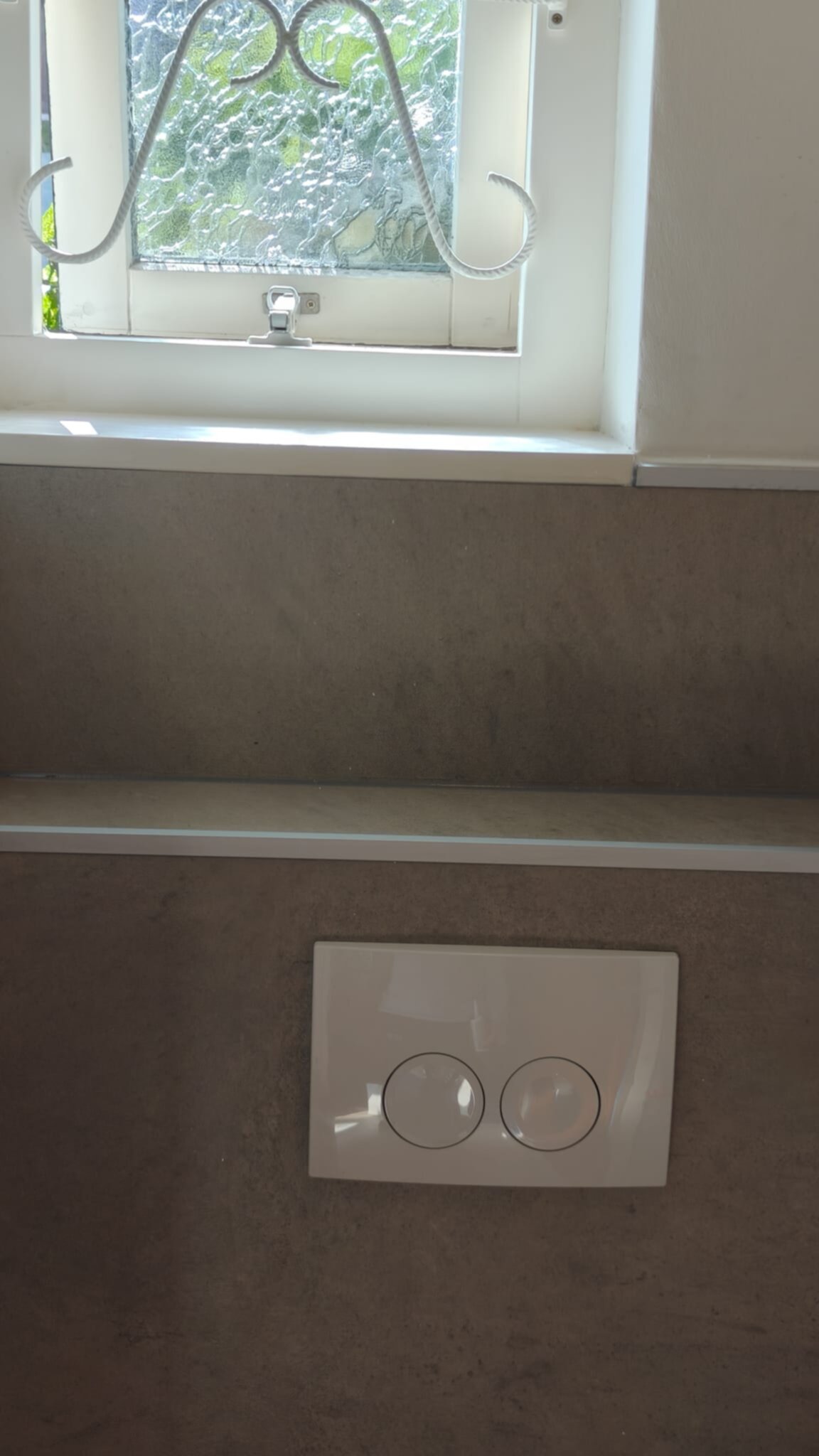 Wit betegelde badkamer wand met lichtschakelaar en raam