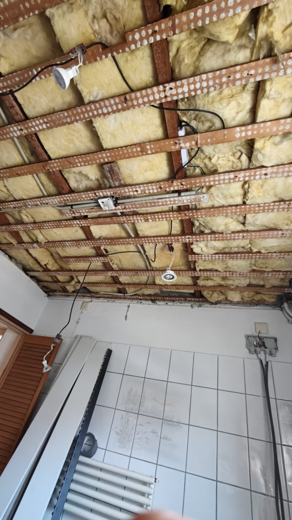 Open plafond met zichtbare isolatie en houten balken in badkamer