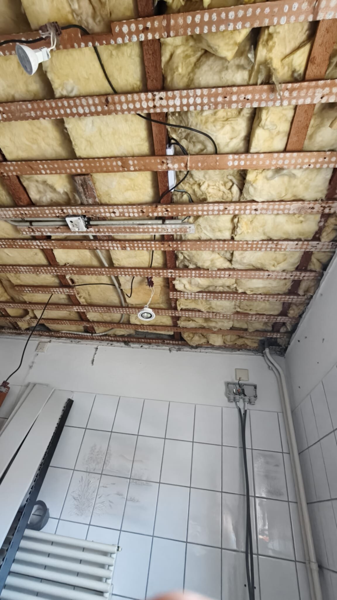 Open badkamer plafond met zichtbare houten balken en isolatie