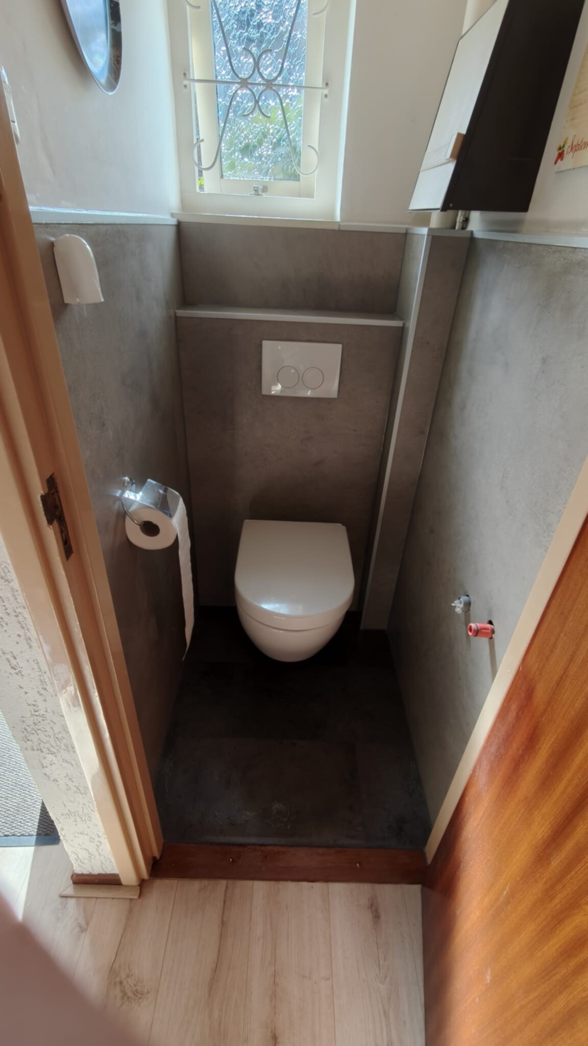 Wit toilet in kleine badkamer met grijze wanden en donkere vloer