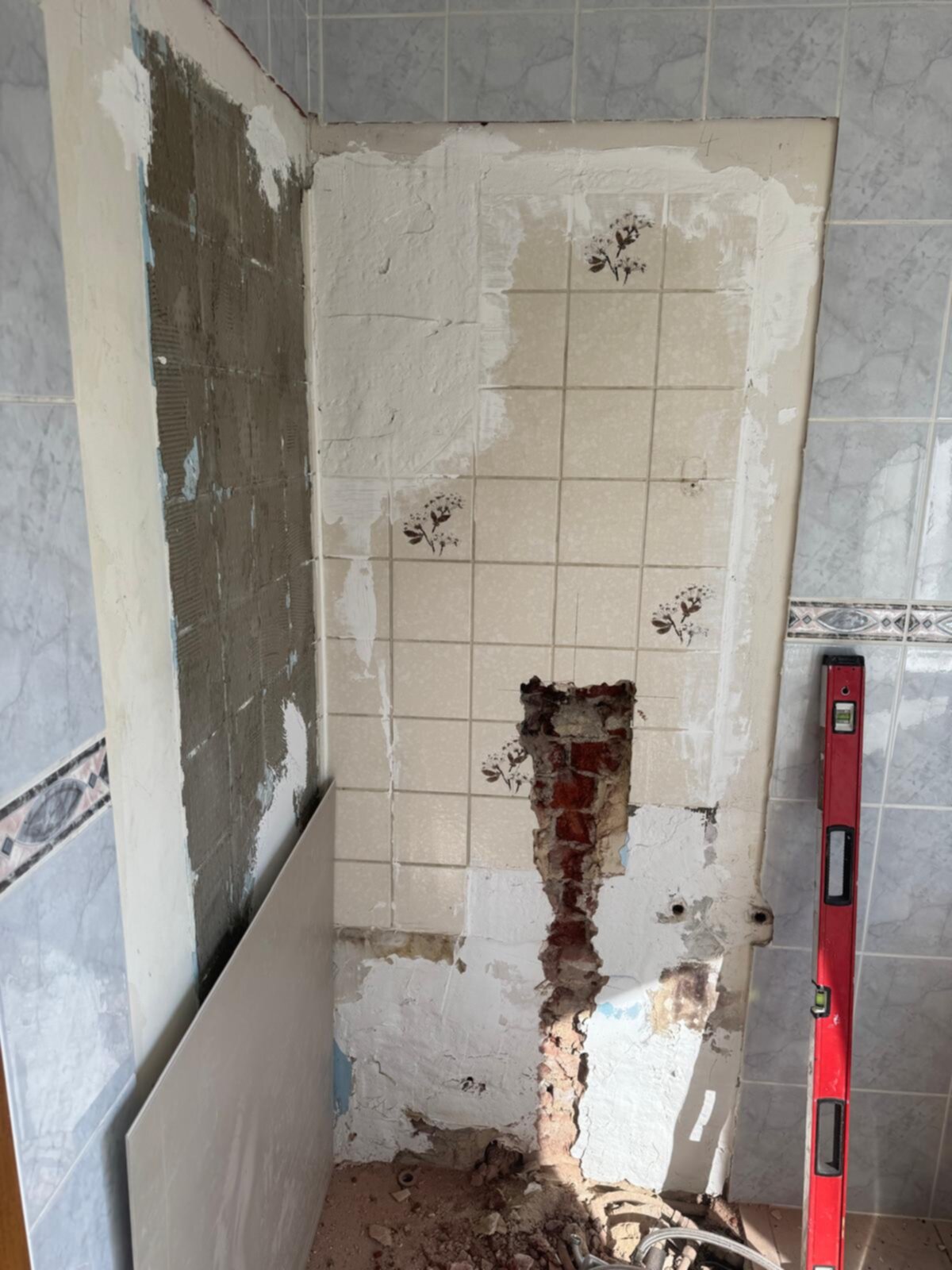 Slecht onderhouden badkamer tijdens renovatie met oude tegels en beschadigde muren