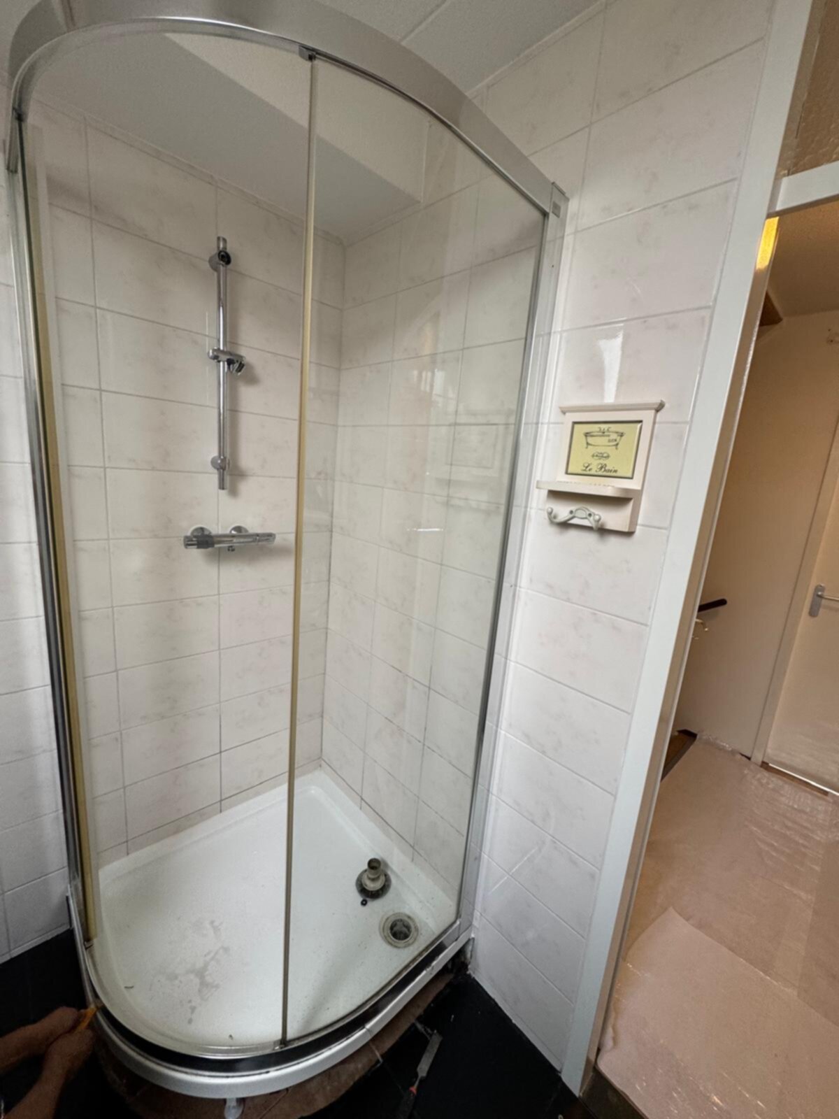Douchecabine met witte tegels en glazen deur in renovatie fase