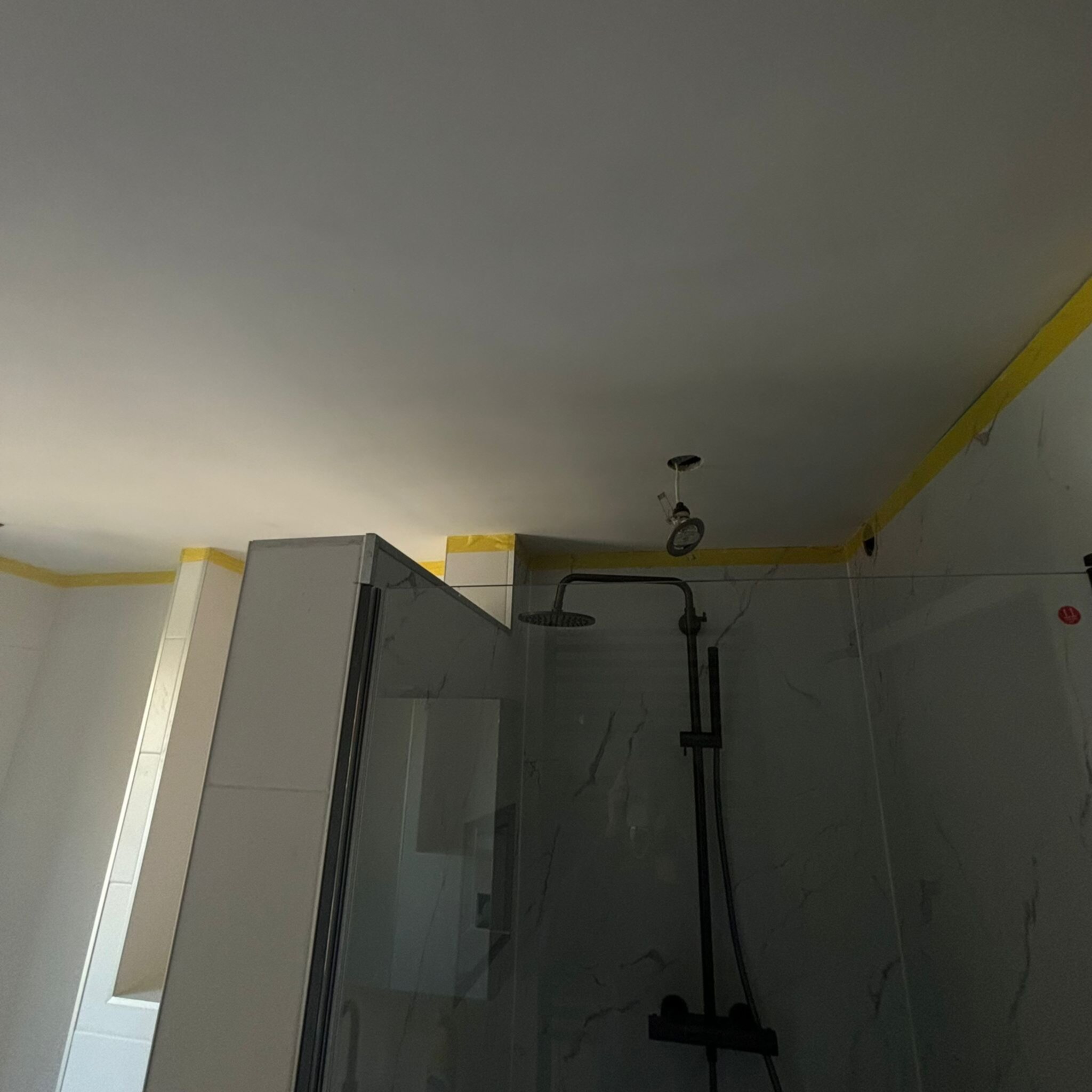 Schilderwerk in badkamer, douche met glazen deur en witte marmeren tegels