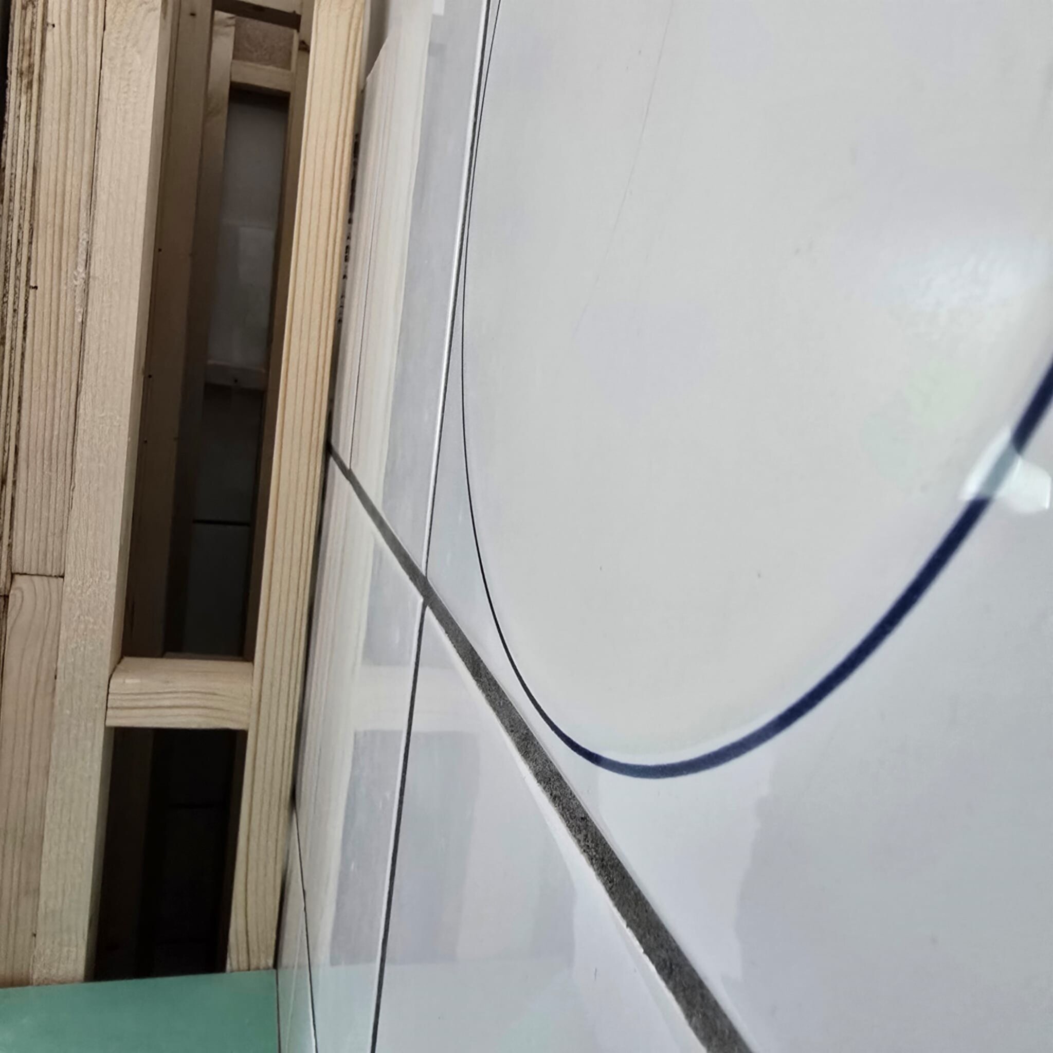 Grote witte tegel met grijze lijnen in een badkamer tijdens renovatie