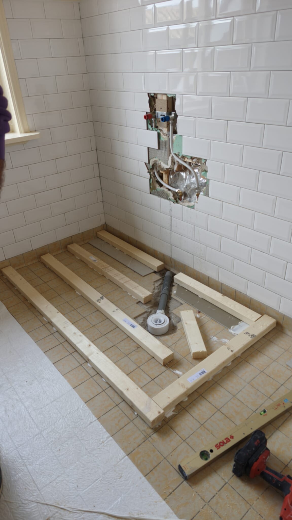 Badkamer renovatie in uitvoering met houten ondervloer en gereedschap