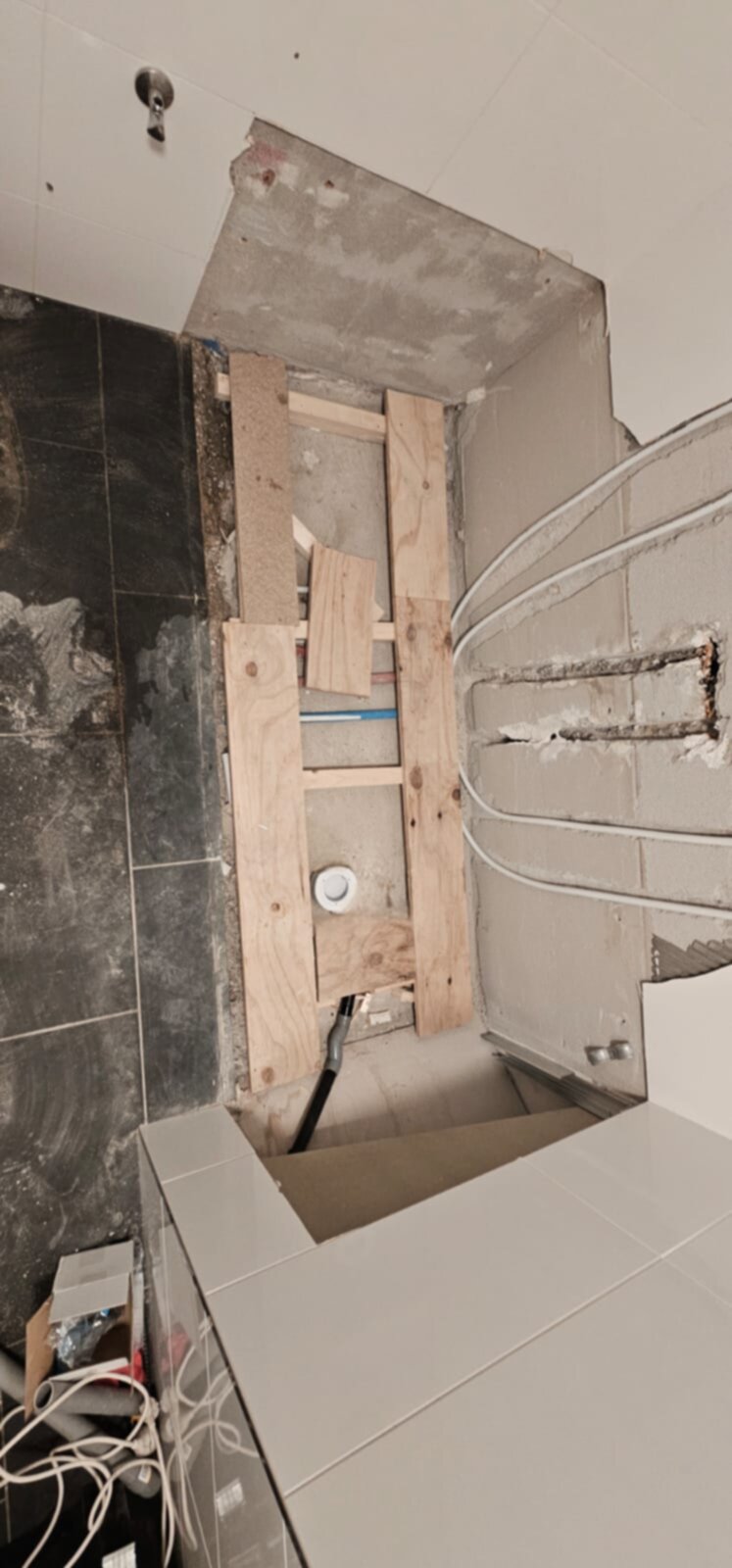 Badkamer renovatie in uitvoering, houten constructie en grijze tegels