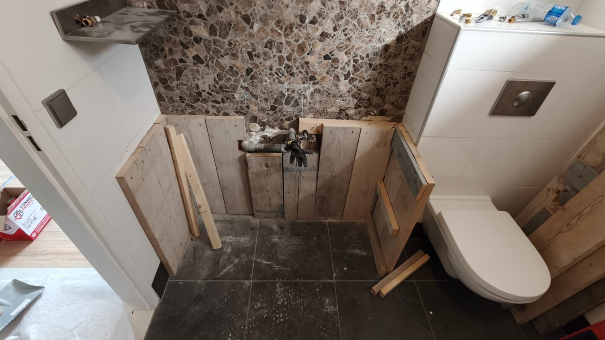 Badkamer in renovatie, houten panelen en marmeren muur tijdens工事