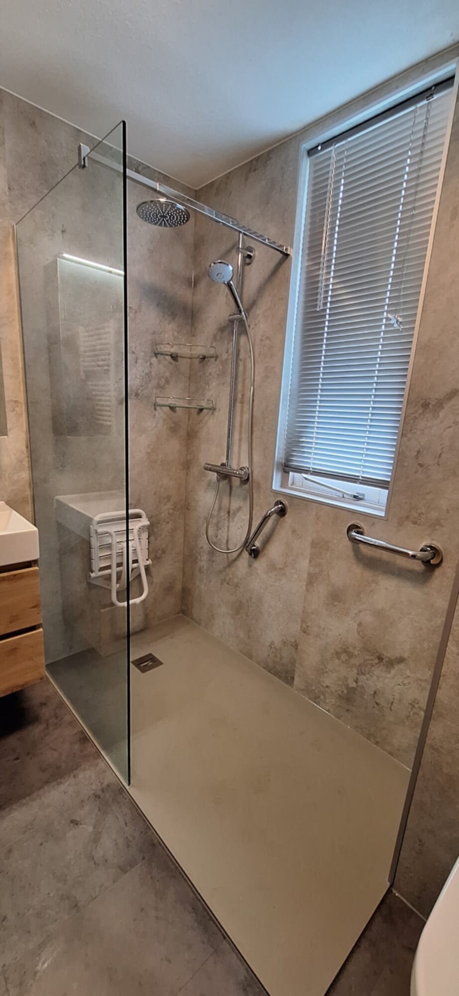 Douche met glazen schuifdeur en betegelde wanden in grijze marmerlook