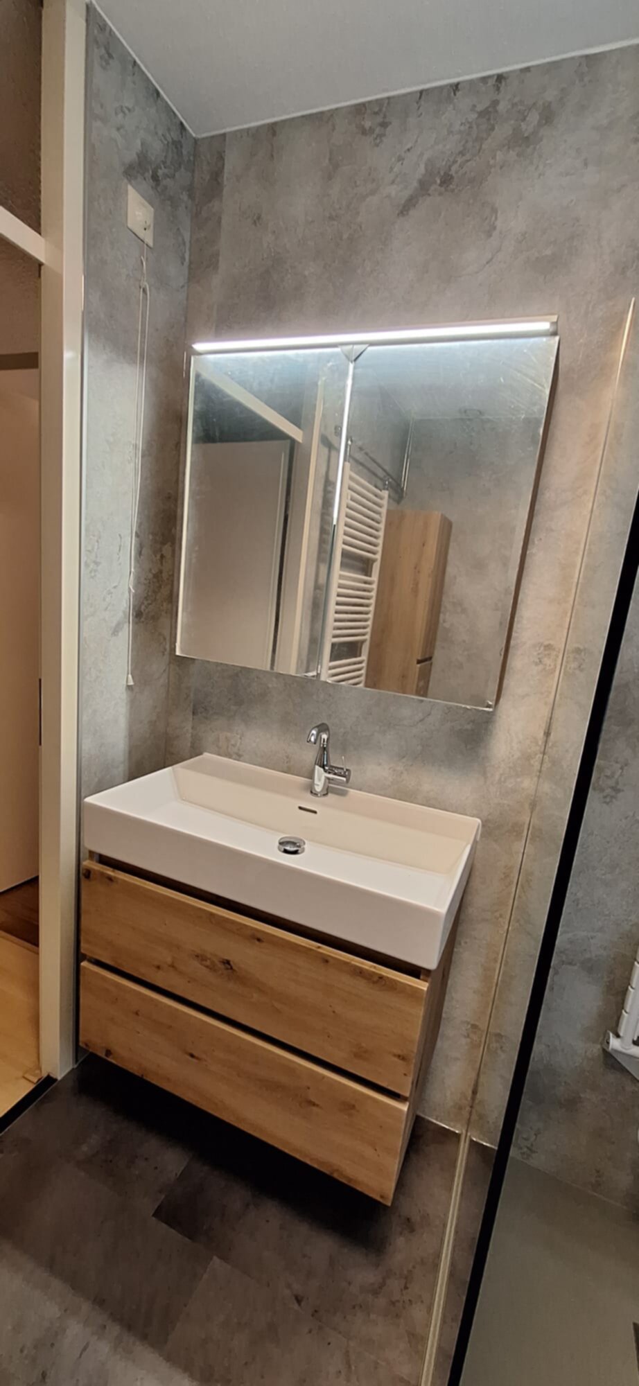 Moderne badkamer met houten wastafel en verlicht spiegel