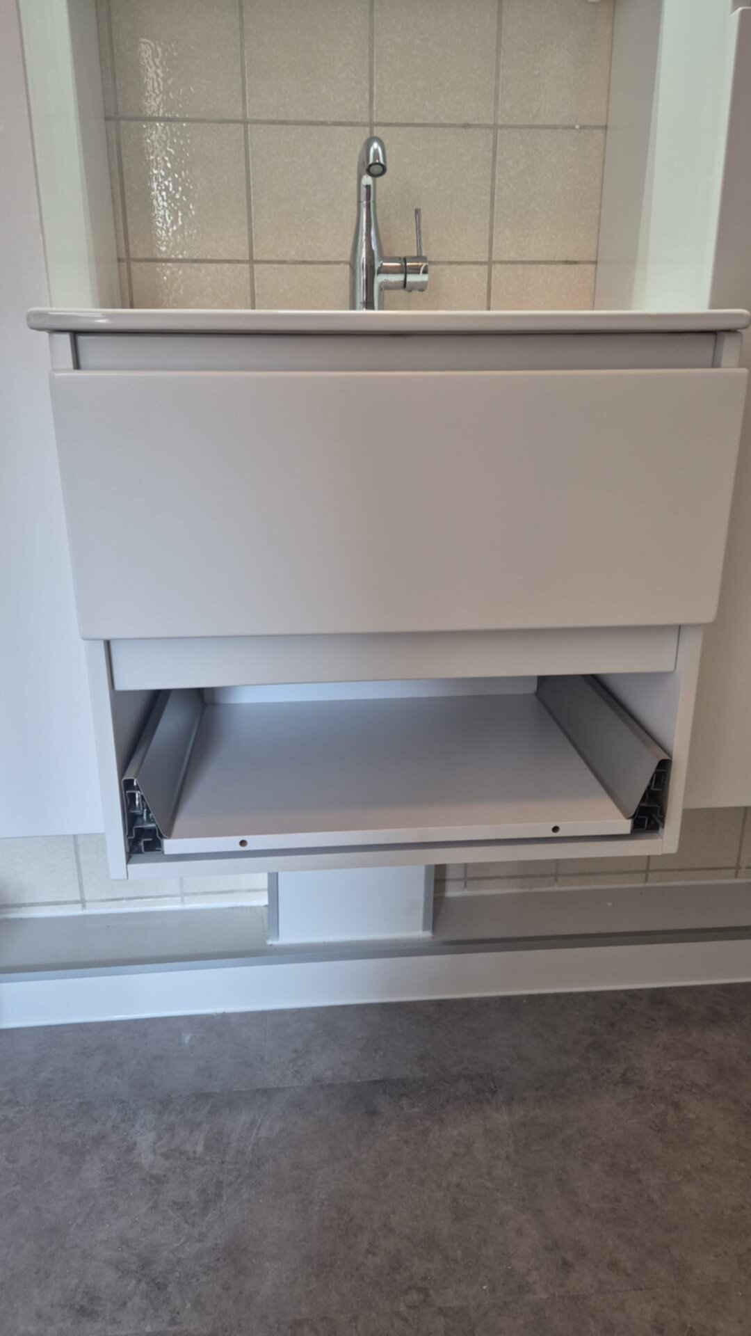 Wastafel met witte kast en open lade, chroom kraan, beige tegelwand