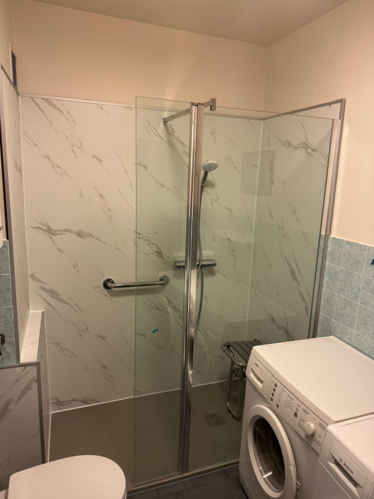 Douche met glazen deur en marmerlook tegels in moderne badkamer
