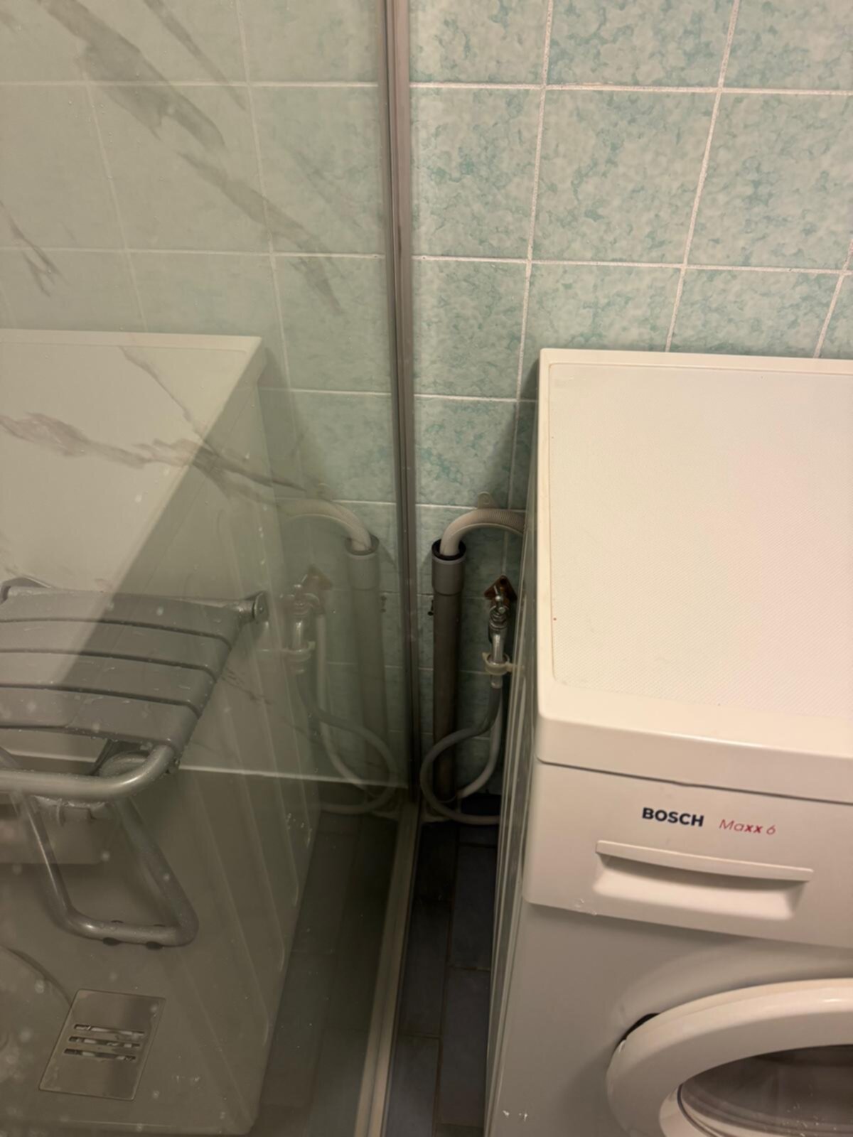 Badkamer met douche, wasmachine en blauwe tegelwanden