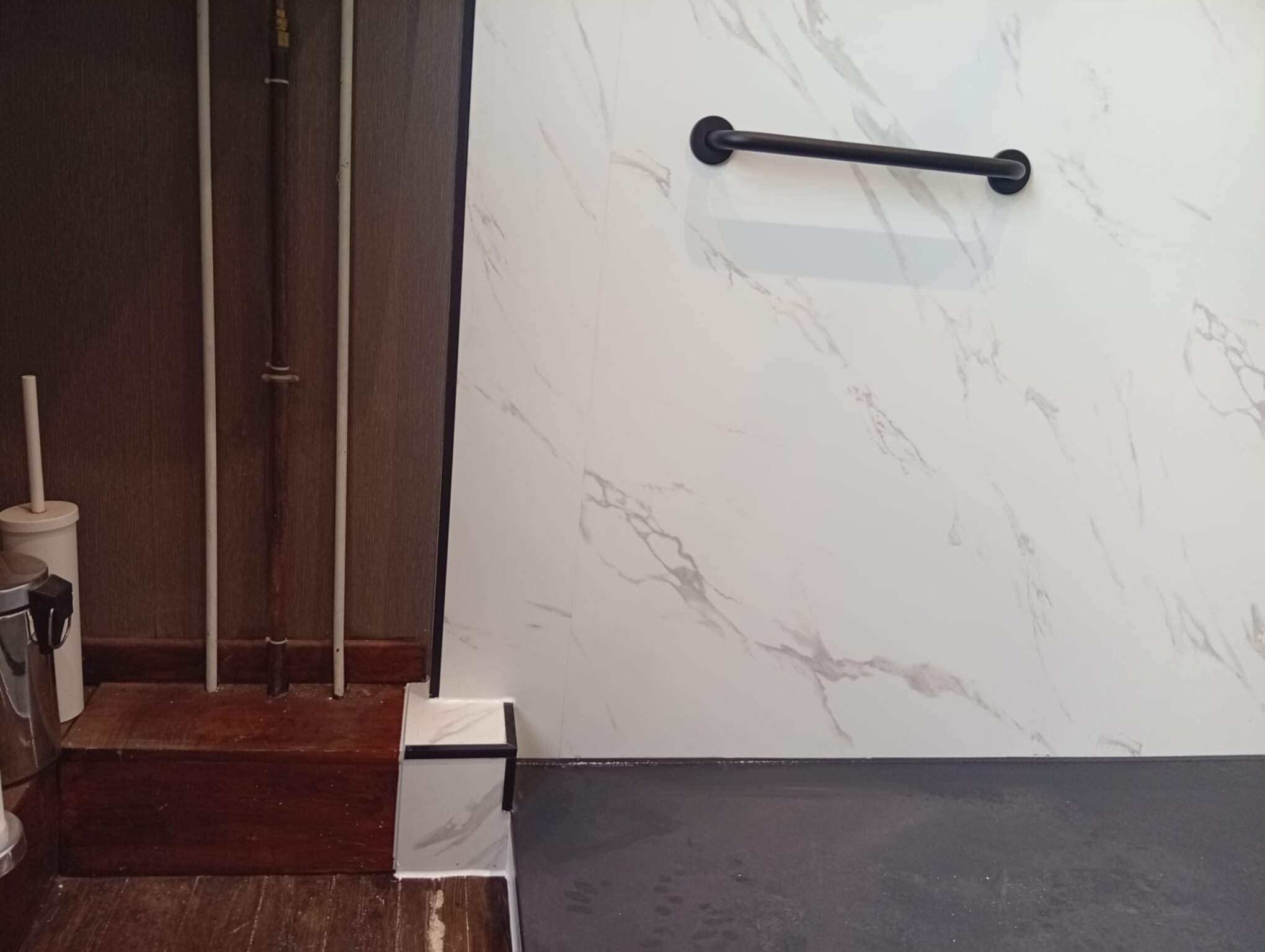Wit marmeren tegelwand met grijze marmerpatronen en zwarte handgreep in moderne badkamer