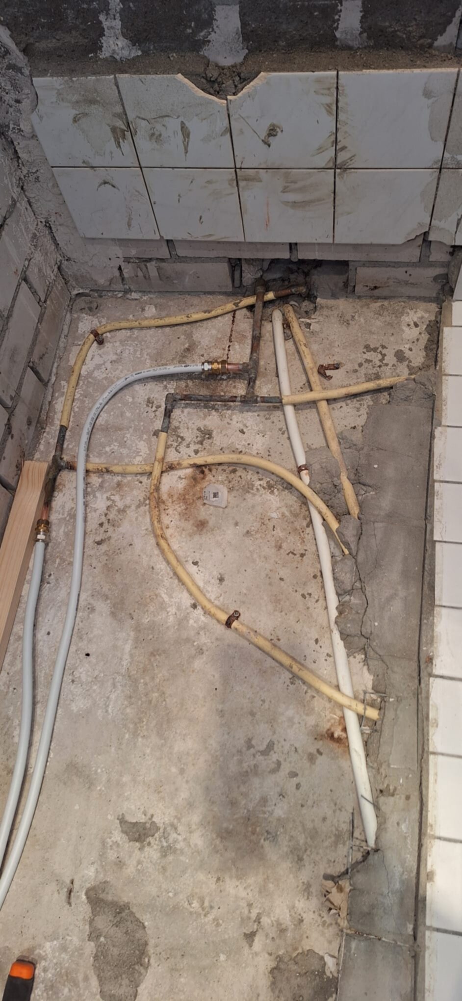 Slechte staat badkamer vloer met blootliggende leidingen en tegelwerk