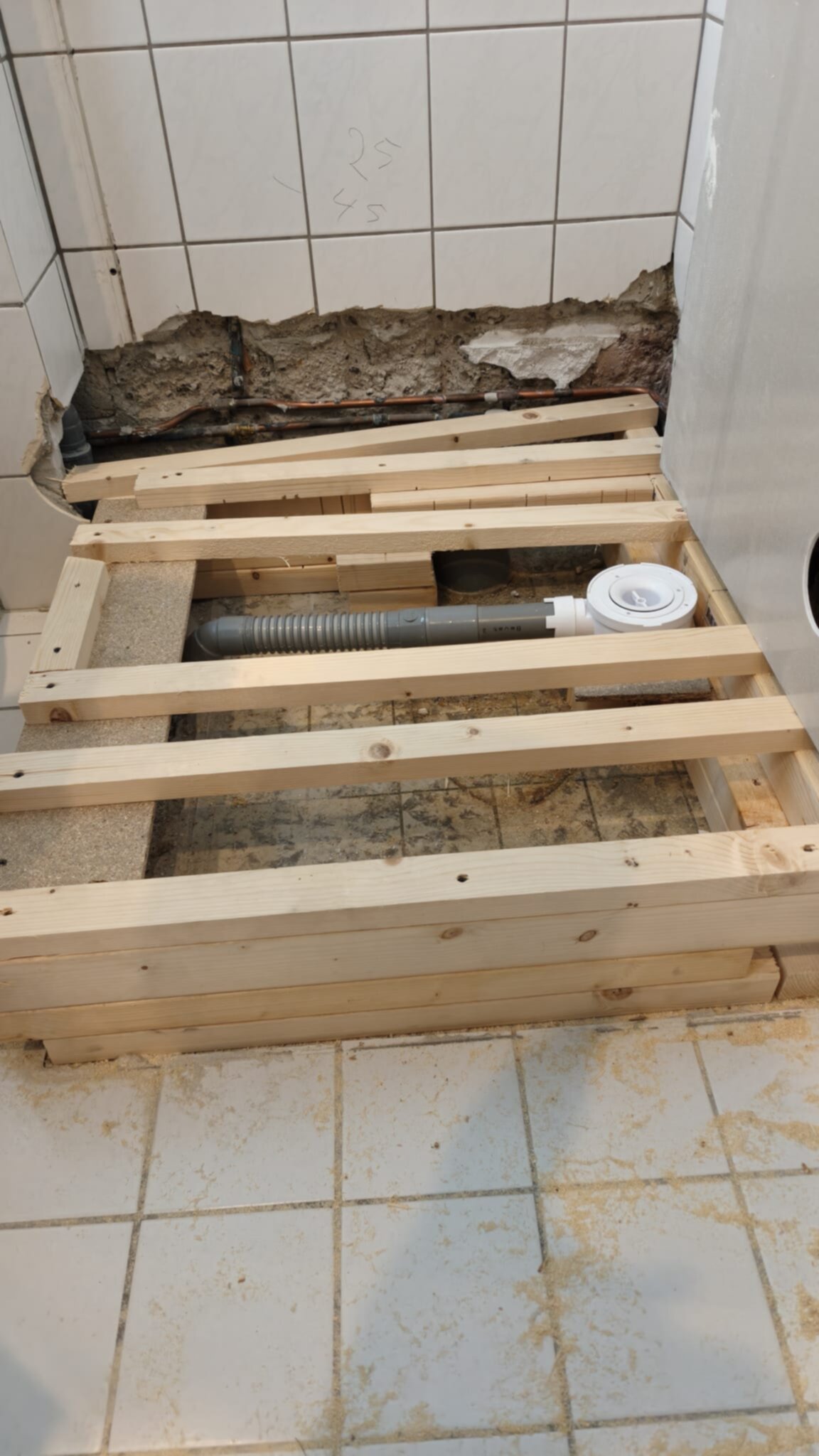 Badkamer renovatie, houten ondervloer voor nieuwe vloer, witte tegelwanden en -vloer