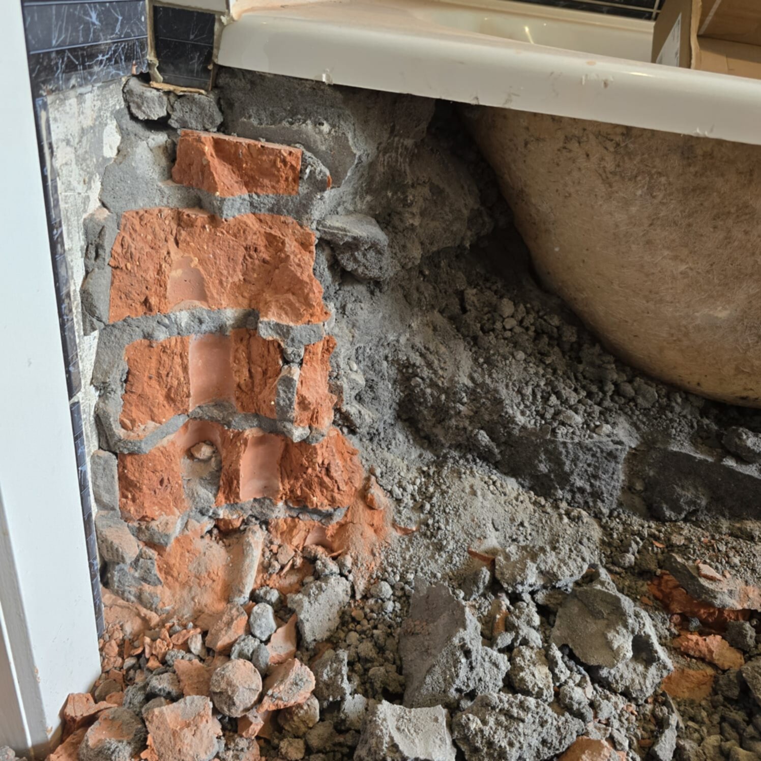 Sloopwerk badkamer met zicht op rode bakstenen en puin op de grond