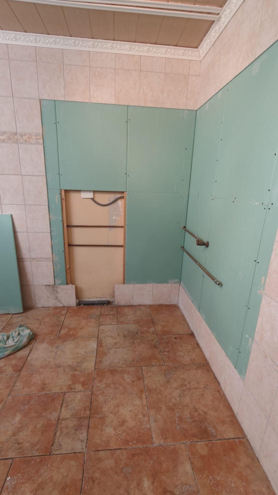 Badkamer tijdens renovatie met groene panelen en betegelde muren en vloer