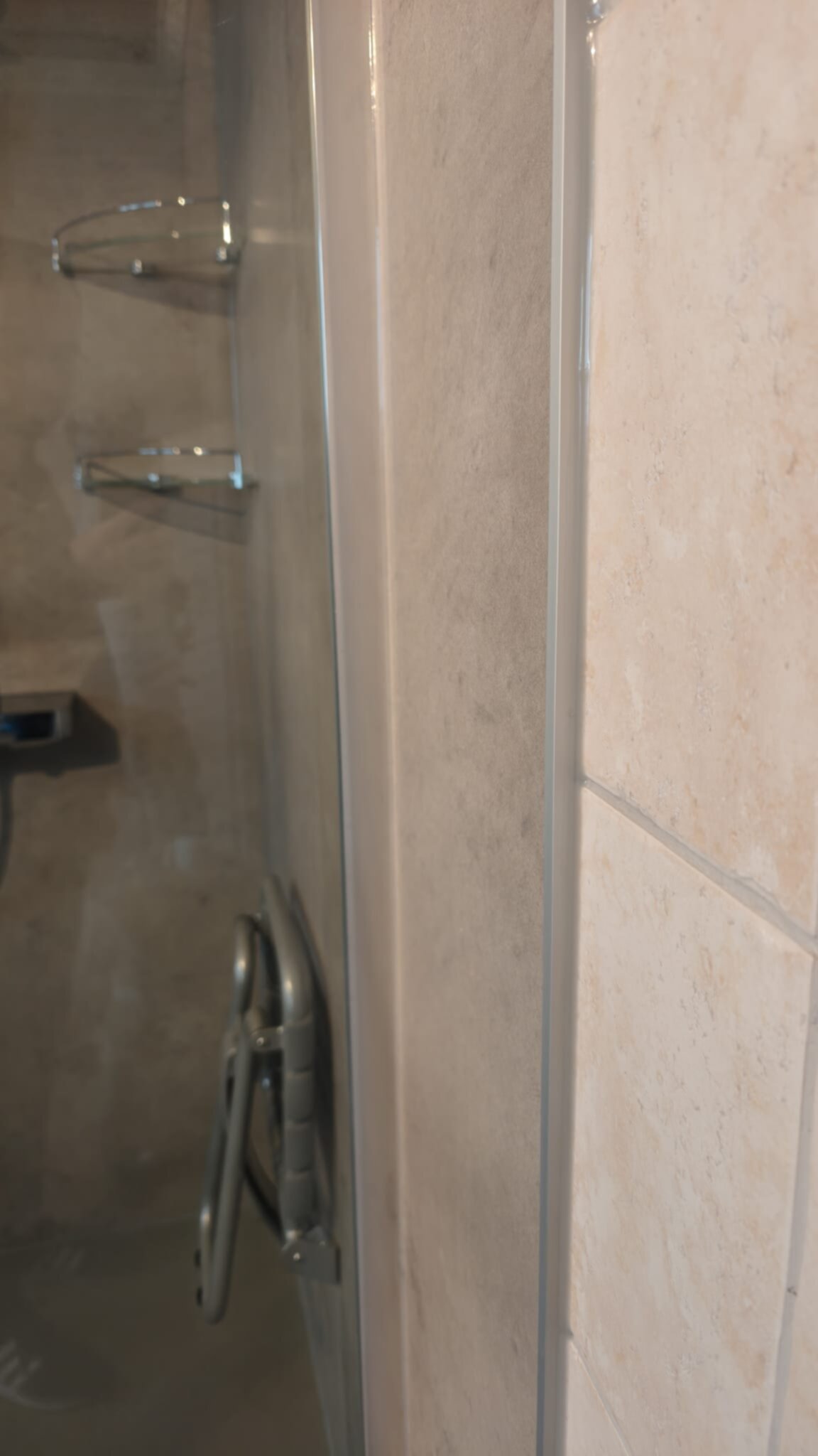 Douchecabine met beige tegels en glazen deur
