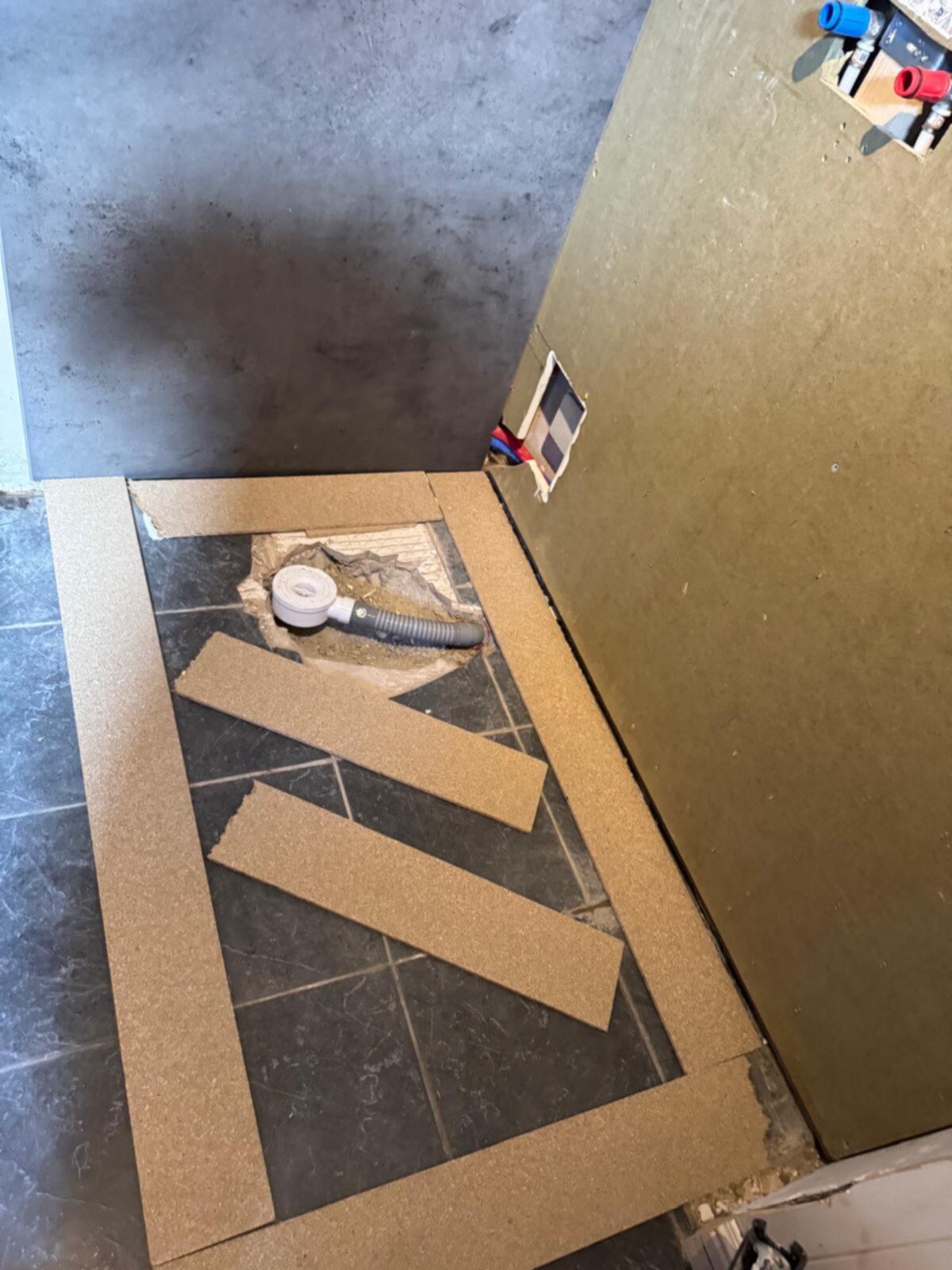 Badkamer renovatie, kartonnen sjabloon op betegelde vloer met grijze en witte tegels