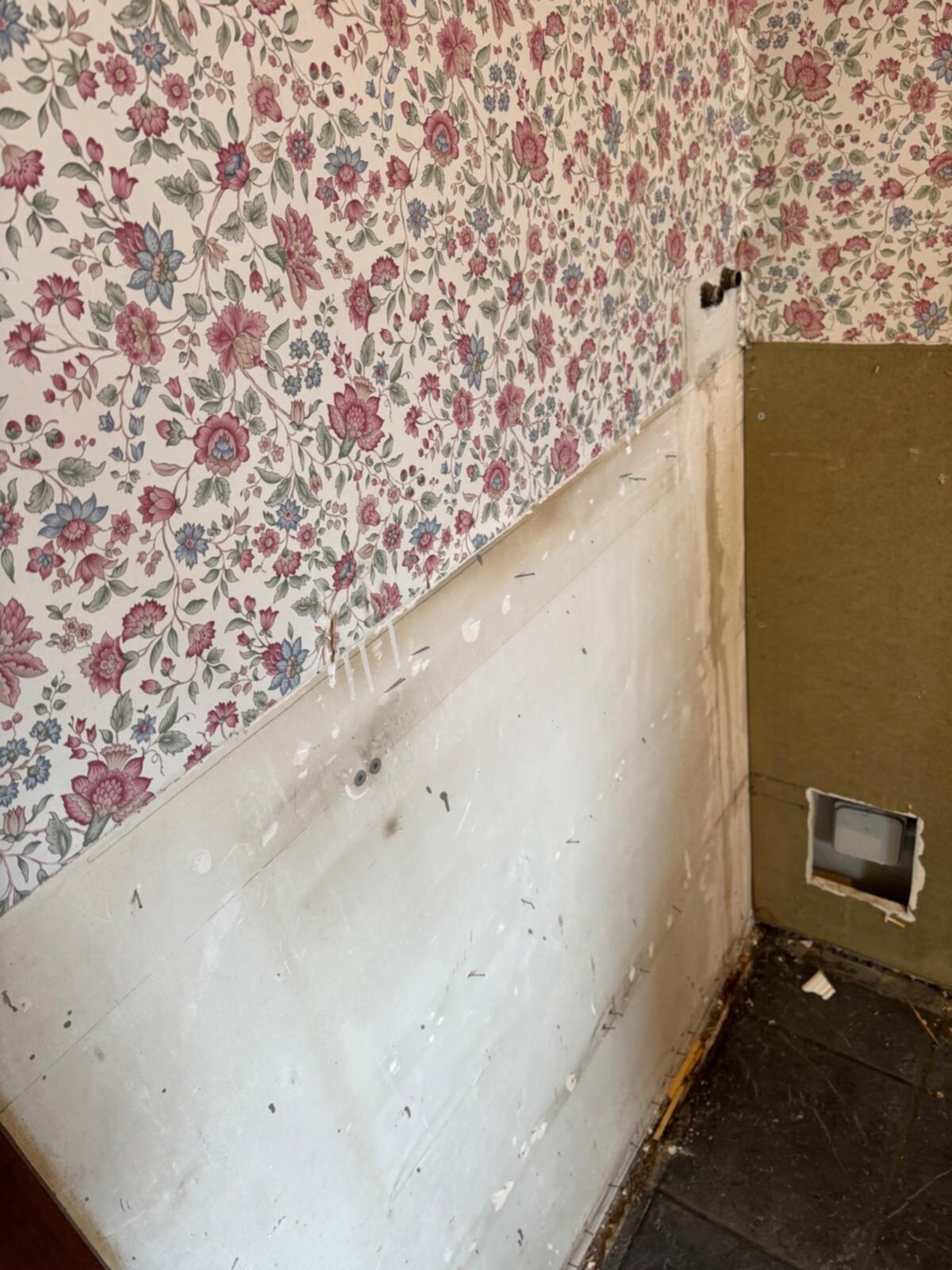 Slechte staat badkamer met bloemen behang en gaten in de muur