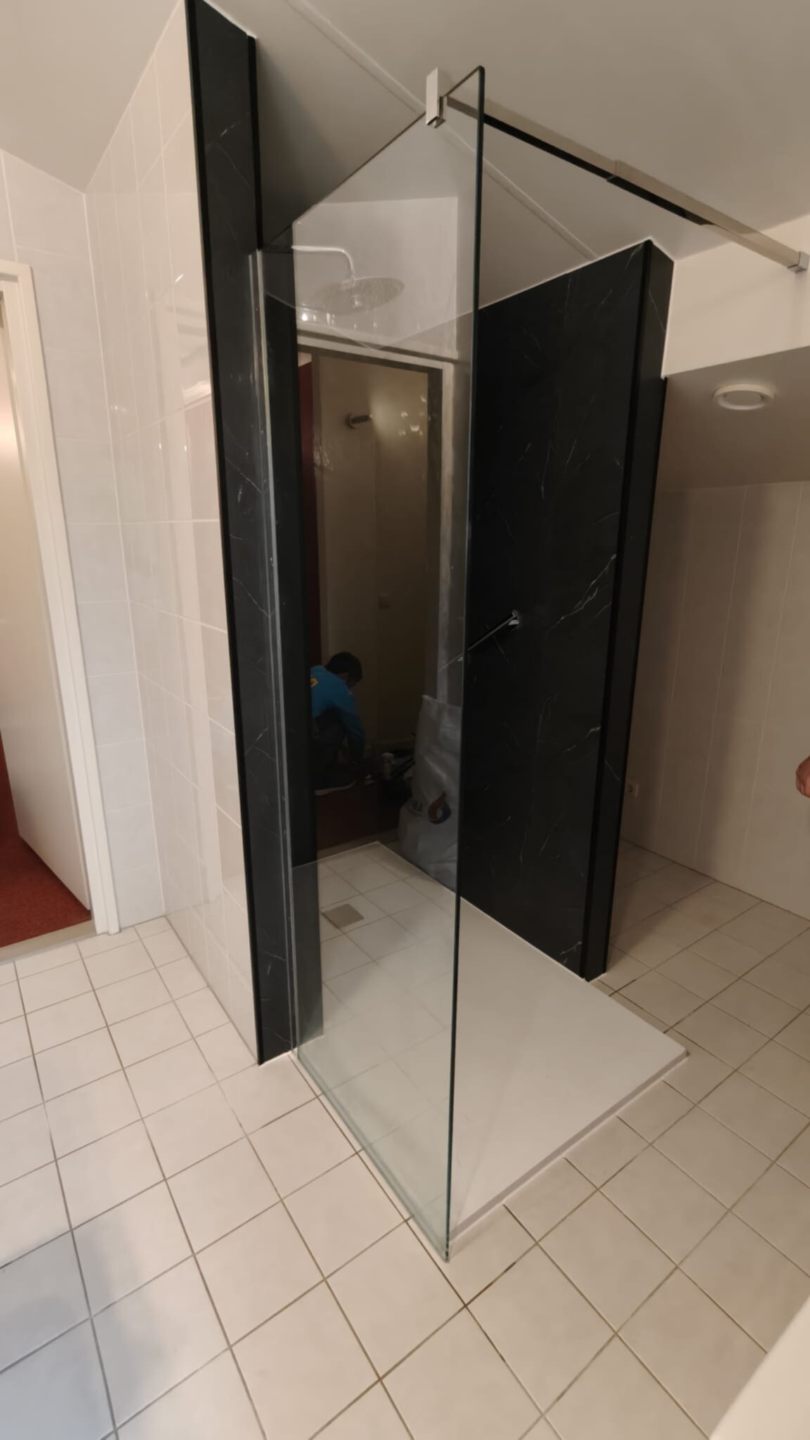Badkamer met zwarte marmeren schuurwand en glazen deur tijdens renovatie