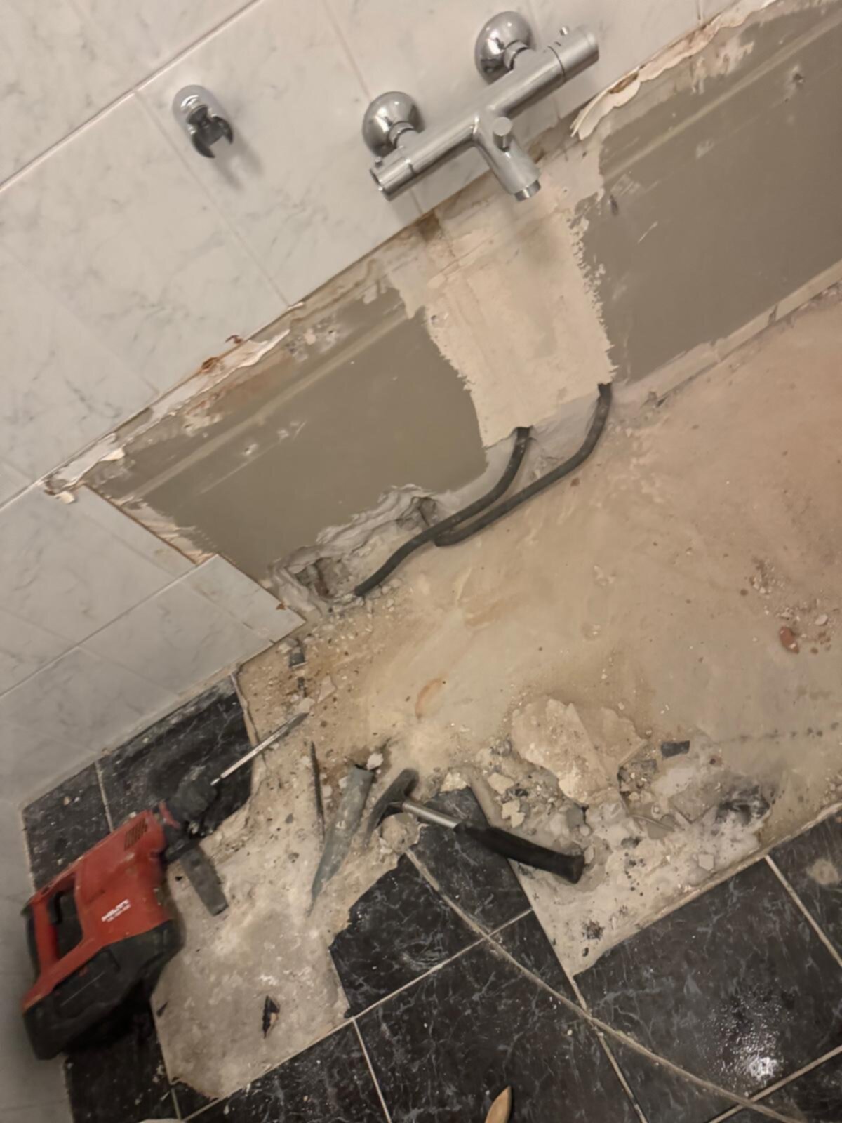 Sloopwerkzaamheden in badkamer met tegel- en marmeren vloer en wanden, gereedschap aanwezig