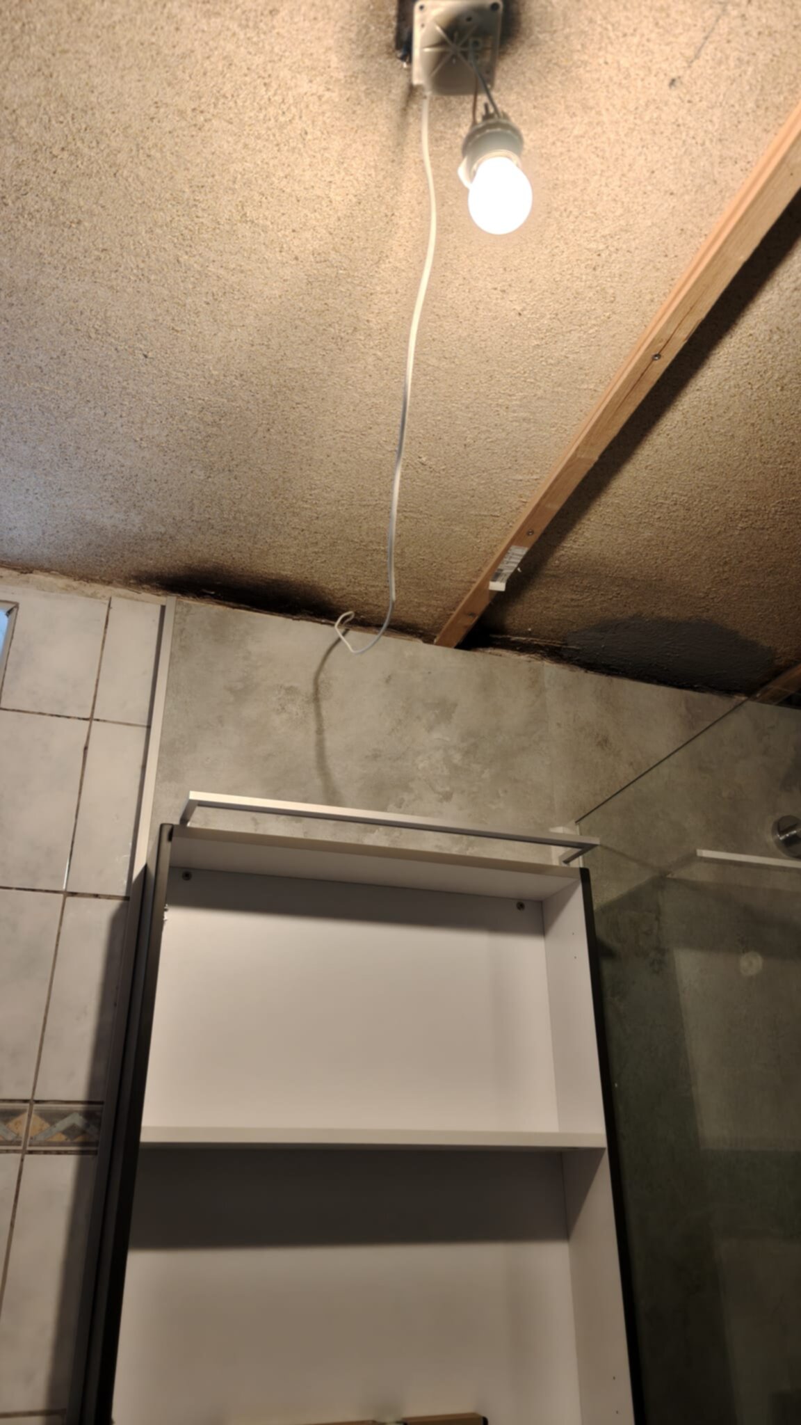 Een bouwput met grijs betegelde muur en een witte kast