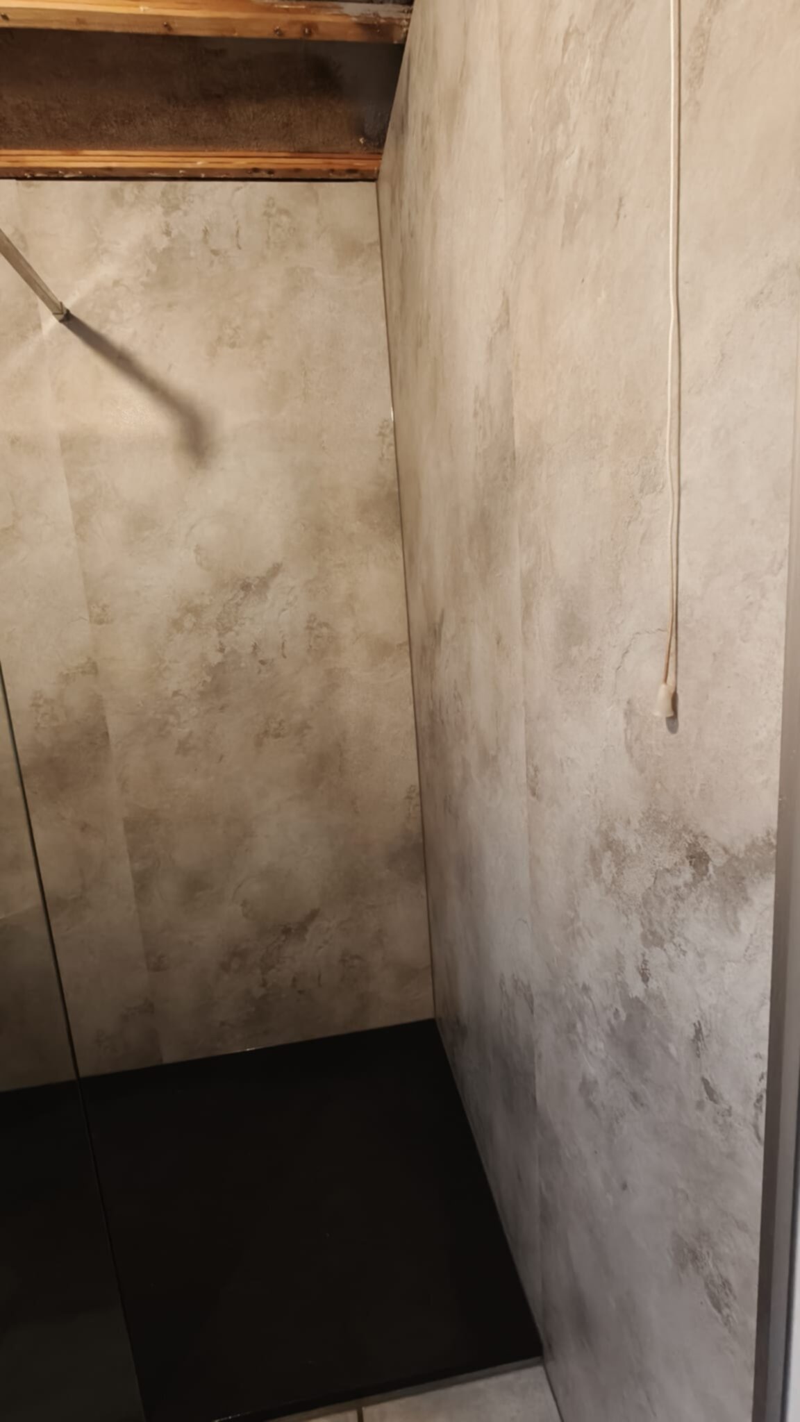 Een betegelde badkamer met grijze en beige marmerlook wanden en een donkere vloer