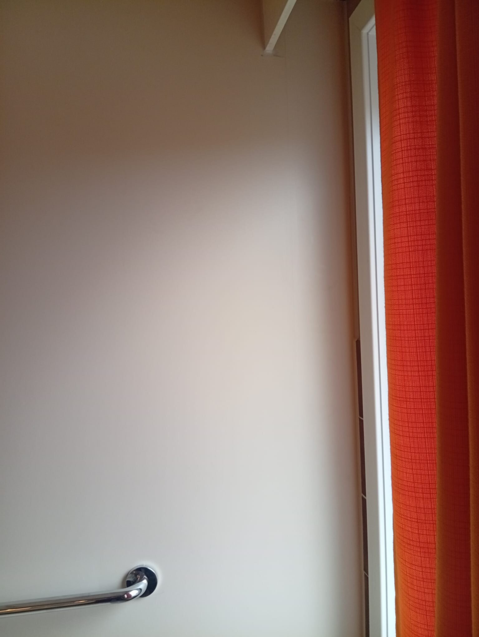 Witte badkamer deur met chromen deurkruk en oranje gordijn