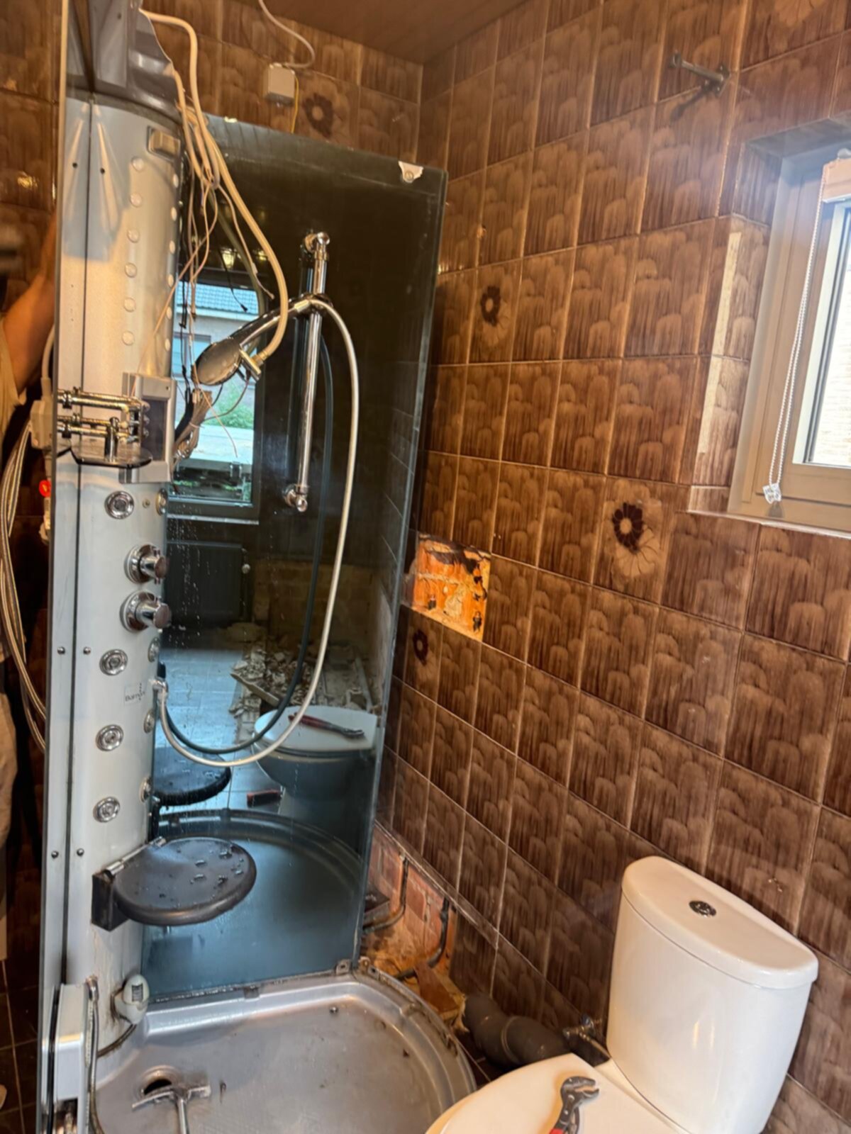 Slechte staat badkamer met bruine tegels en kapotte douche