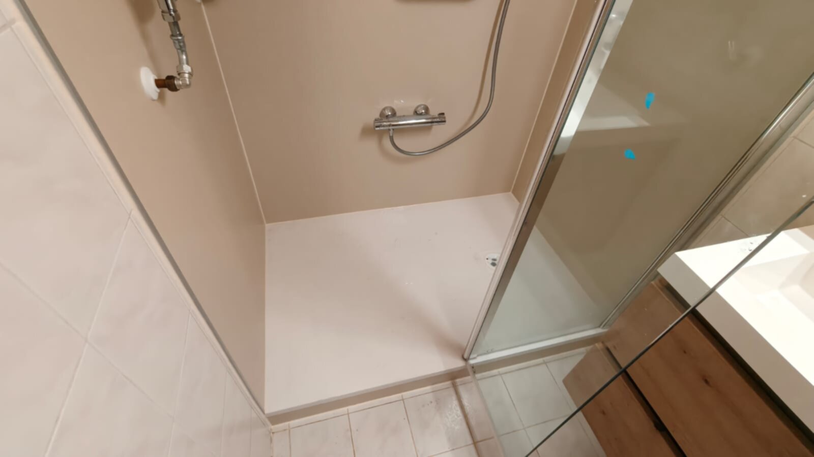 Douchecabine met glazen deur en witte tegelwand