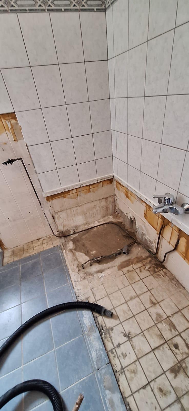 Gedateerde badkamer voor renovatie: oude tegels en sanitair.